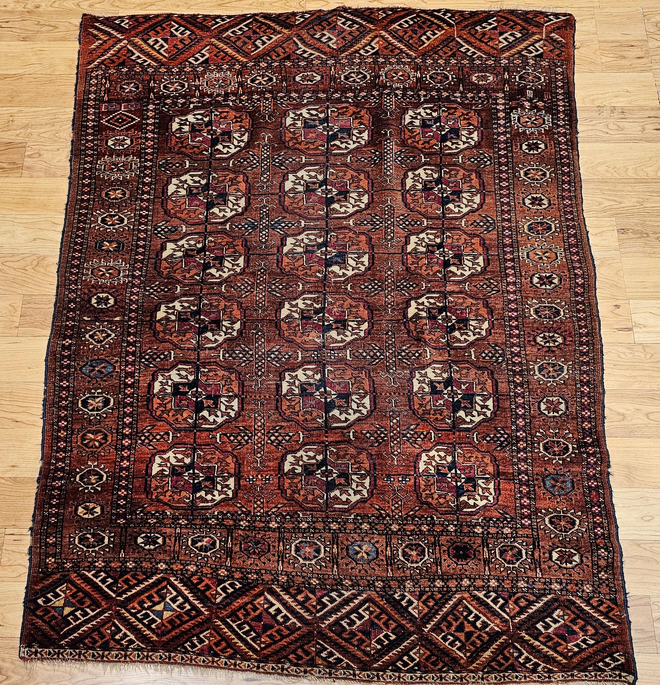 Vintage Turkmen Tekke area rug in an allover small medallion pattern from the late 1800s.  The rug has a beautiful and graceful red background color.  The medallions are in crimson, navy, ivory, and rust.  Rug has a very fine weave with high knot