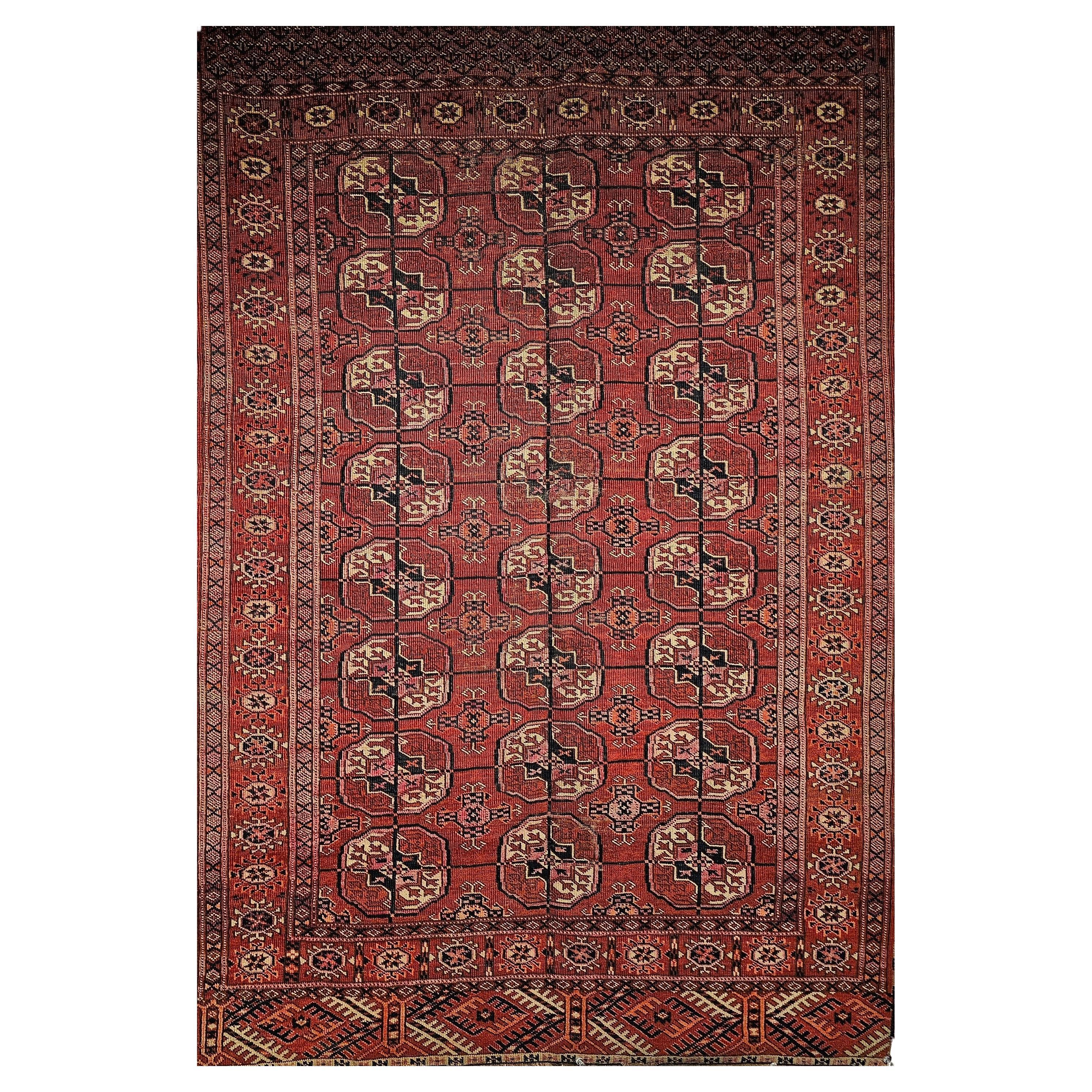 Alfombra Turkmen Tekke Vintage con diseño geométrico en rojo ladrillo, azul marino y rosa