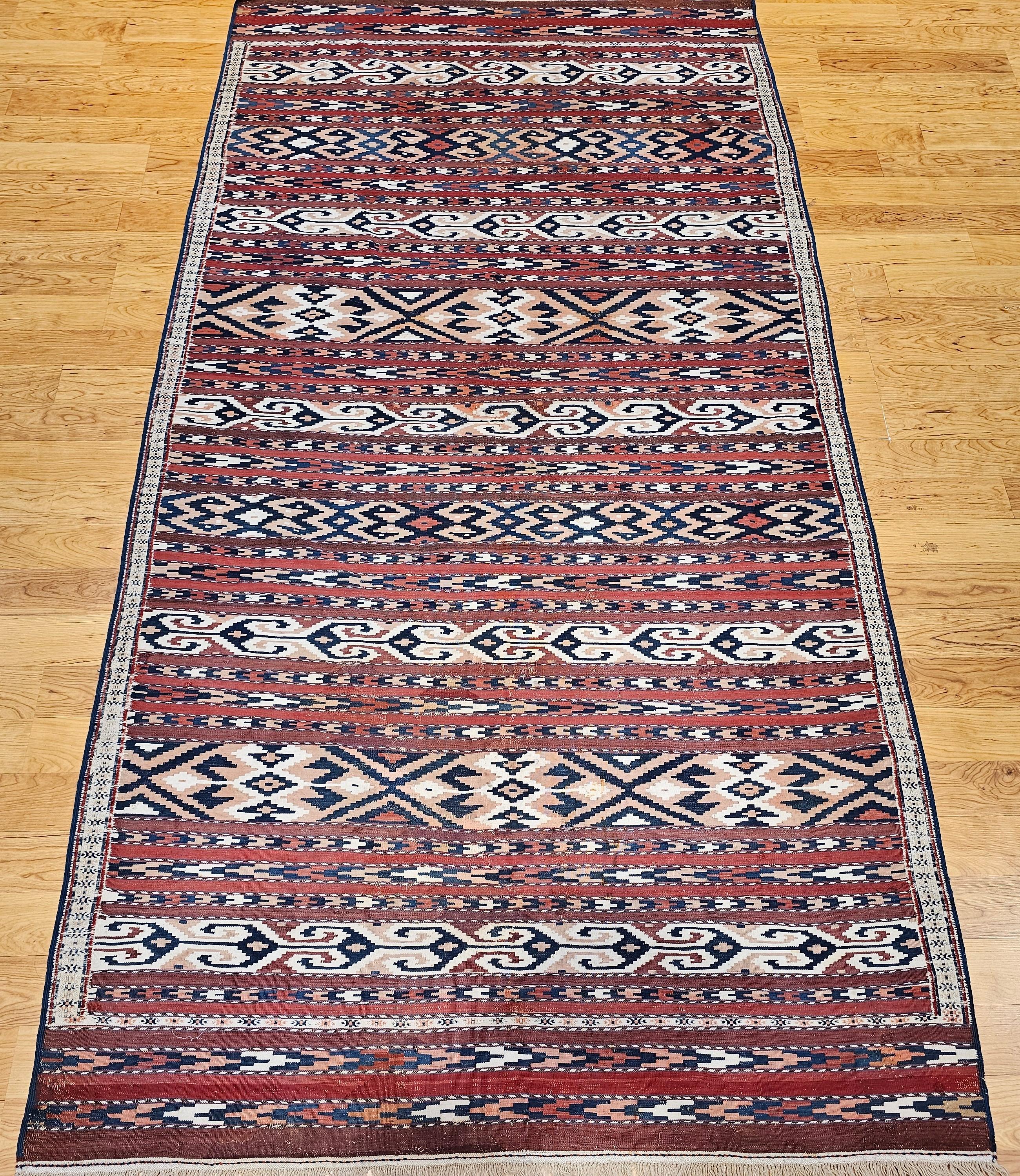 Early 20th century Turkmen Yomut tribal rug from Central Asia in a geometric stripe pattern in dark red with accent colors in French blue, rust, brown, and ivory.   It is a very rare and highly seeked Turkmen kilim with the distinctive “Turkmen
