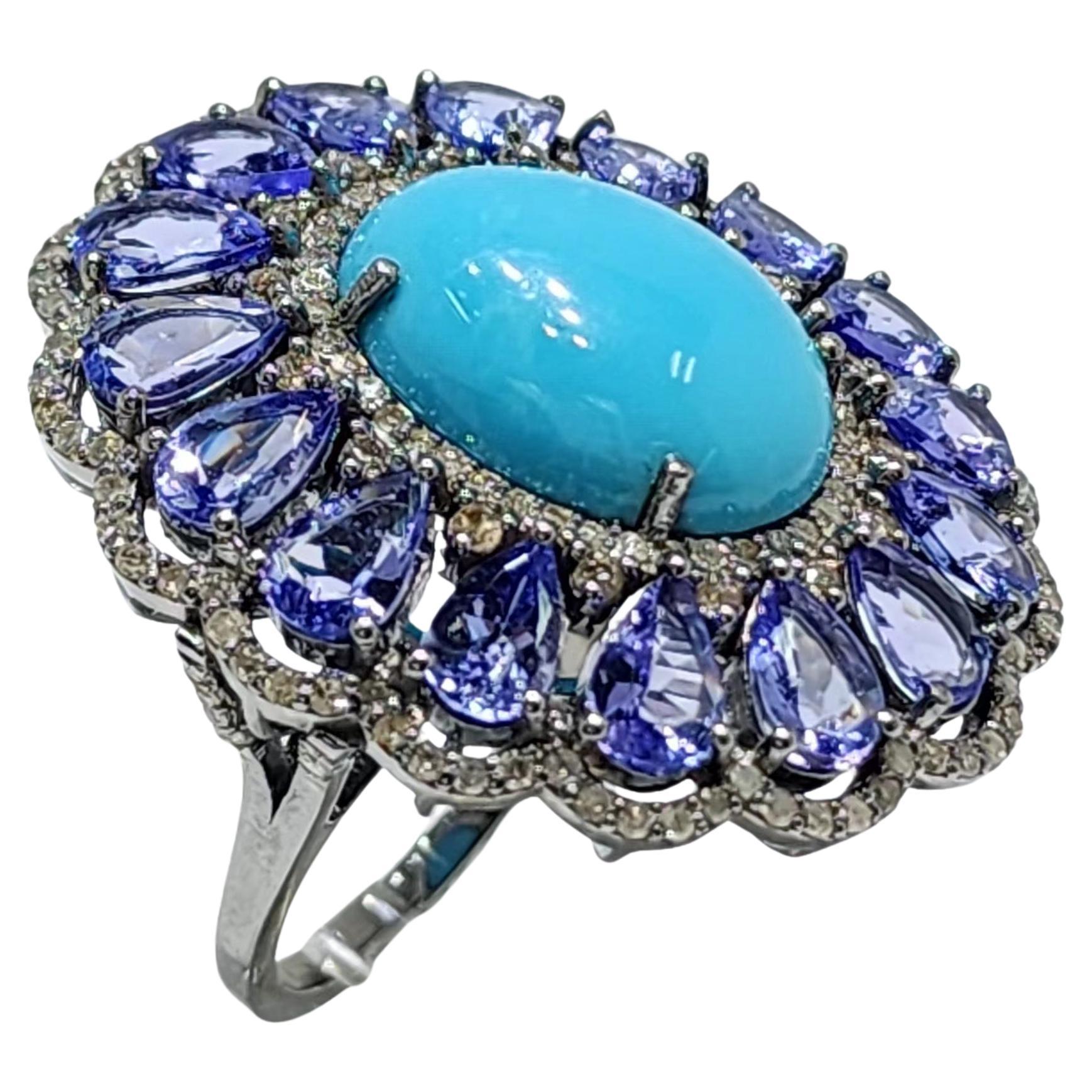 Crafted in lustrous silver, this opulent statement ring showcases a harmonious combination of precious gemstones.  At the center, a vibrant Persian turquoise stone radiates against a halo of 12.25 carats of deep blue Tanzanites and sparkling 1.09