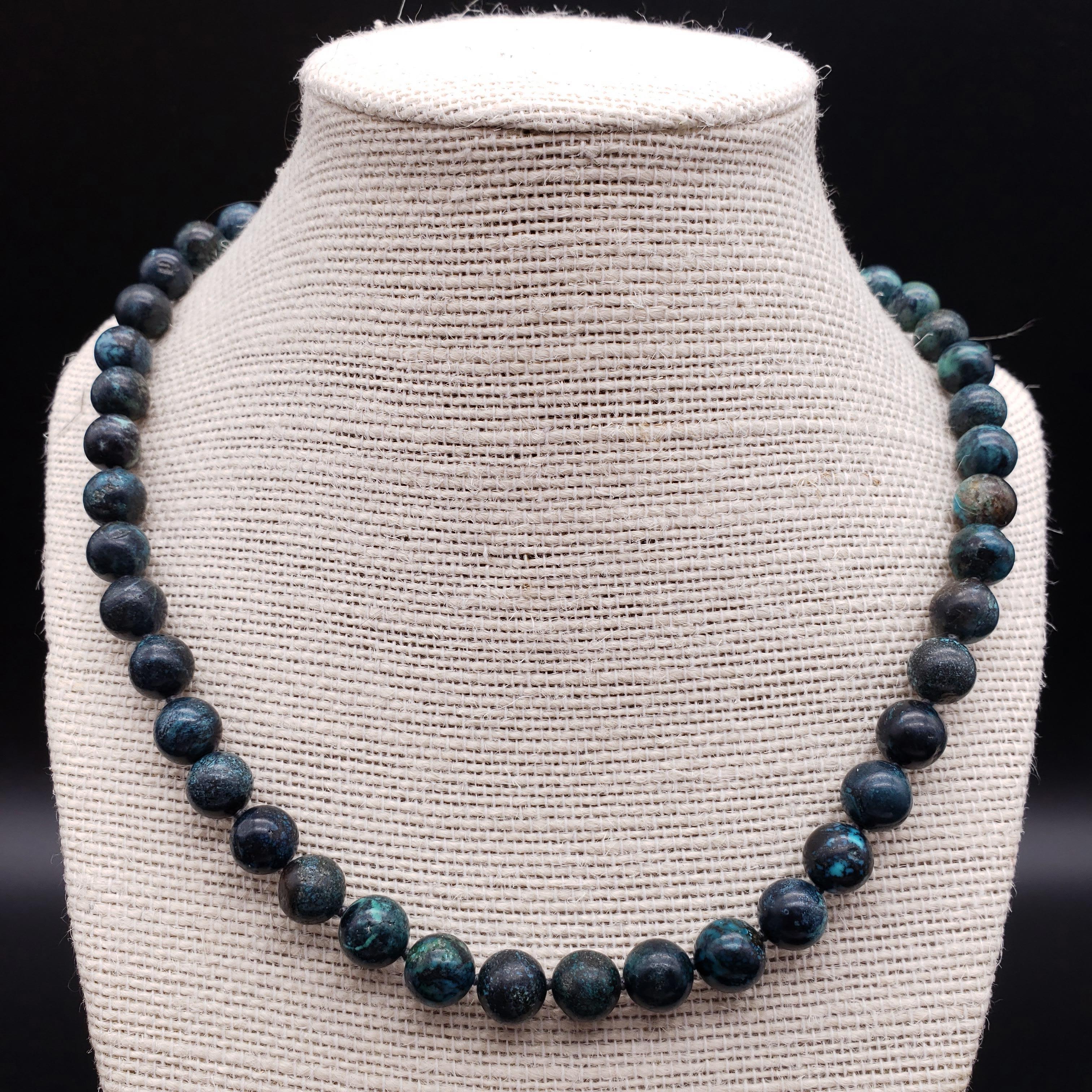 An exquisite vintage turquoise bead necklace. This 18-inch, knotted string necklace features a series of round, 10mm, turquoise beads with exotic-looking matrix patterns. The polished gemstones are a rich, unique, and vibrant color. Fastened with a