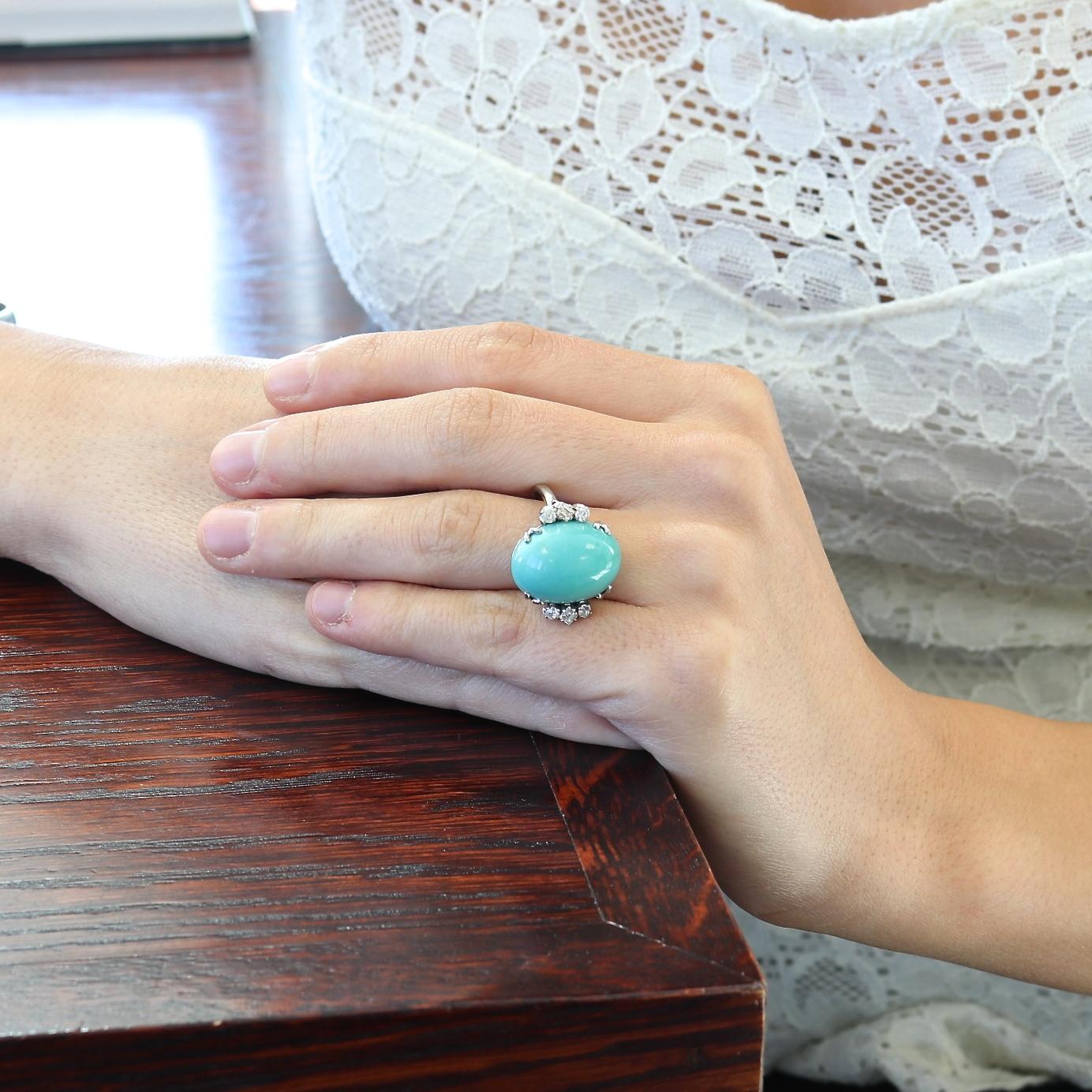 Turquoise is a daring color ready to capture anyone's attention. Featuring a vibrant cabochon cut turquoise that is eloquently accented on either side by an array of white, lively diamonds. Crafted in platinum. Ring size 5 1/4 and can easily be