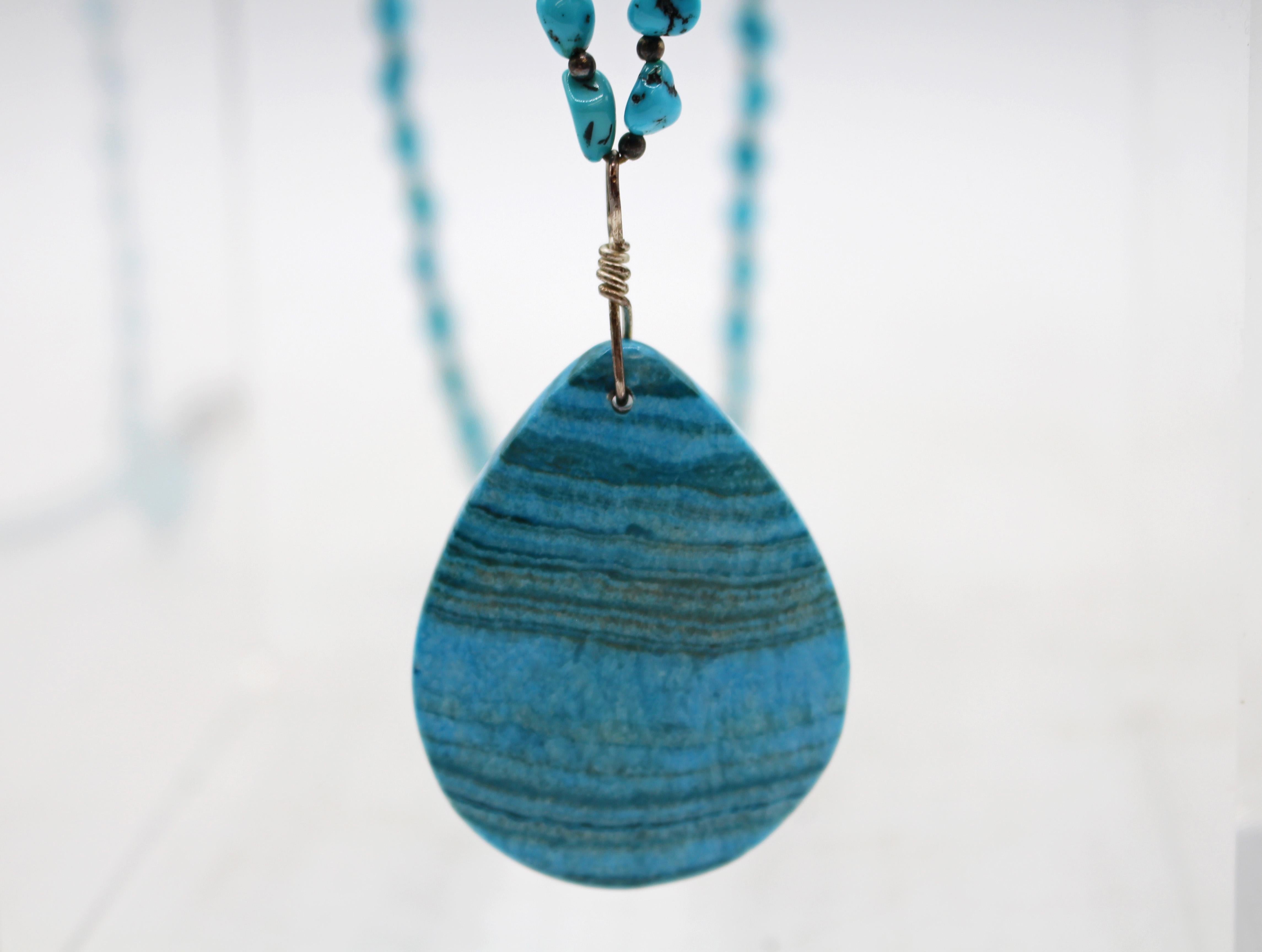 Vintage turquoise Native American necklace. Repetitive, graduated turquoise round, flat beads with central drop of 2 turquoise nuggets flanking a coral nugget. Sterling silver conical & bead clasp. Provenance: Silver Eagle Trader, 2/16/1975. Clasp