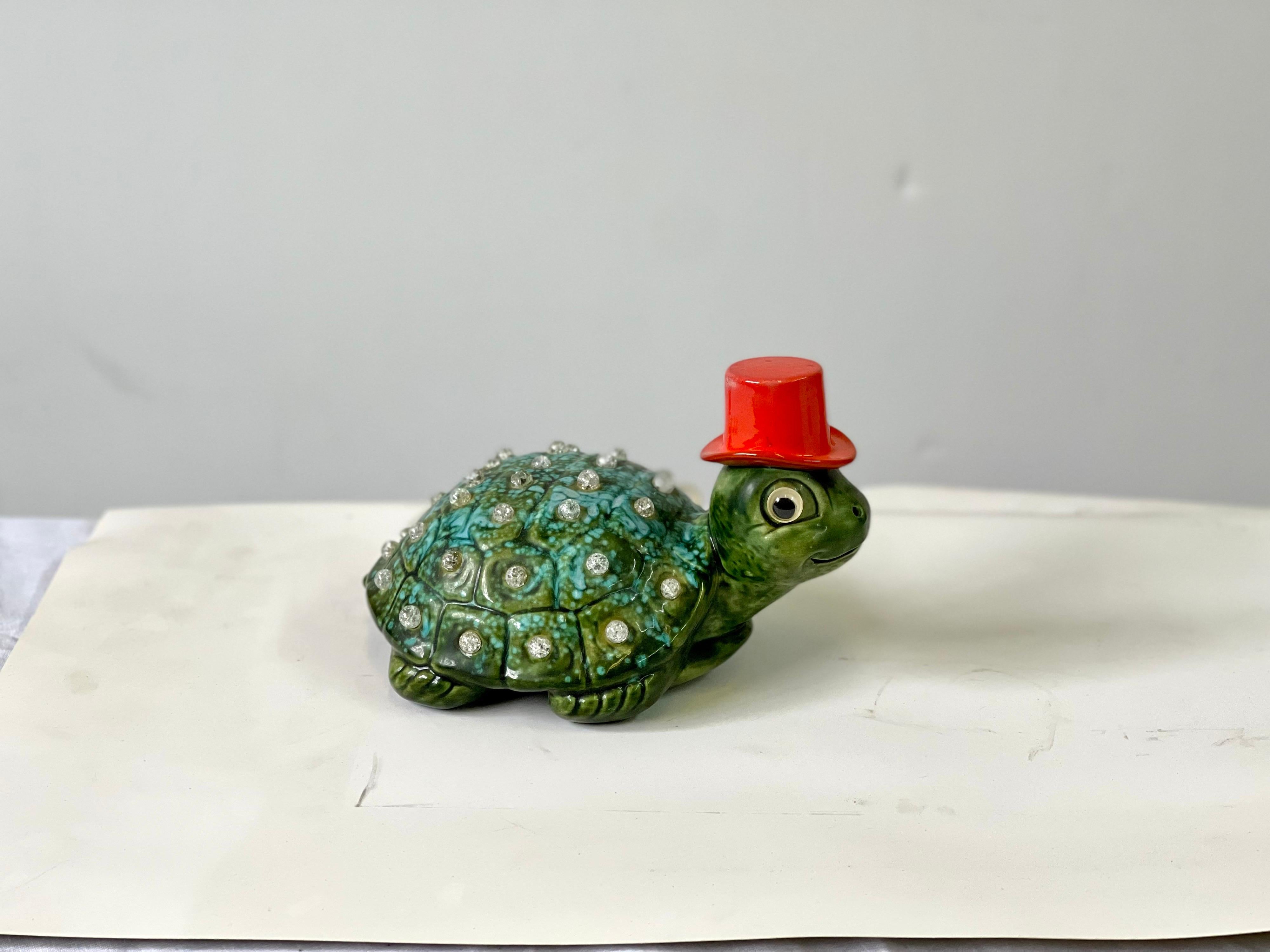 Charming midcentury lamp or nightlight made of ceramic in the form of a turtle. The shell is glazed turquoise and green and is decorated with small crackled glass balls that light up. This adorable turtle is sporting a red-orange top hat and has