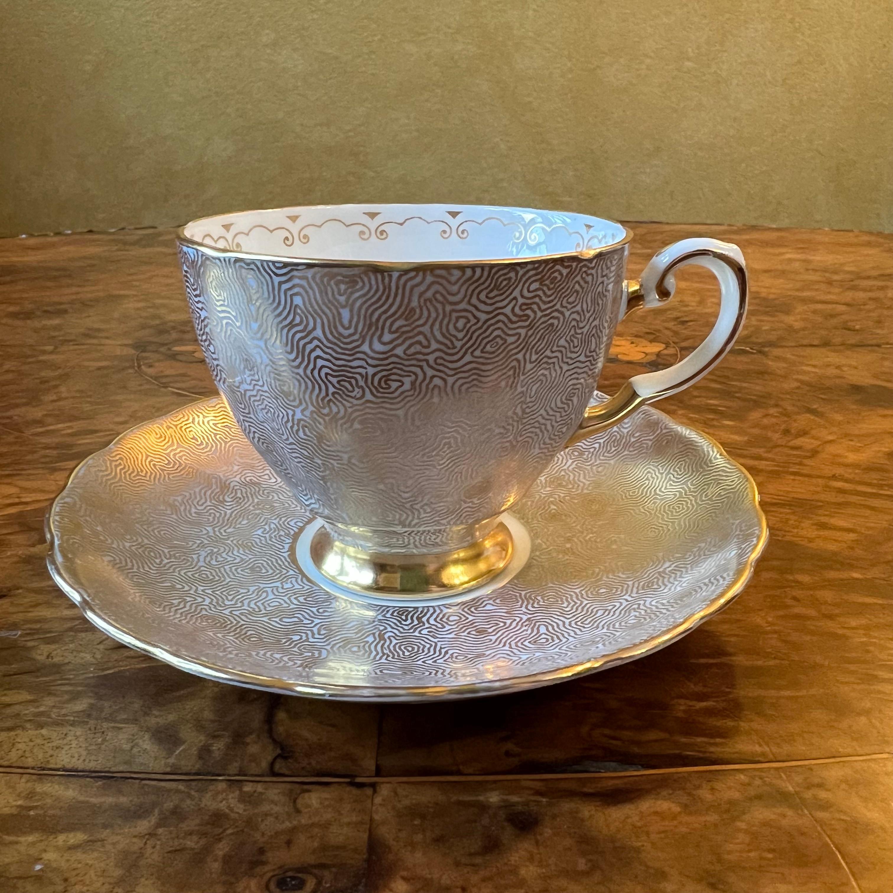 Wavey gold patter over a blue background, some ware to gold, stamped Tuscan.

Circa: 1930s

Material: Porcelain

Country Of Origin: England 

Measurements

Cup: 5.5cm high, 9.5cm length, 7cm width 

Saucer:  12.5cm diameter 
