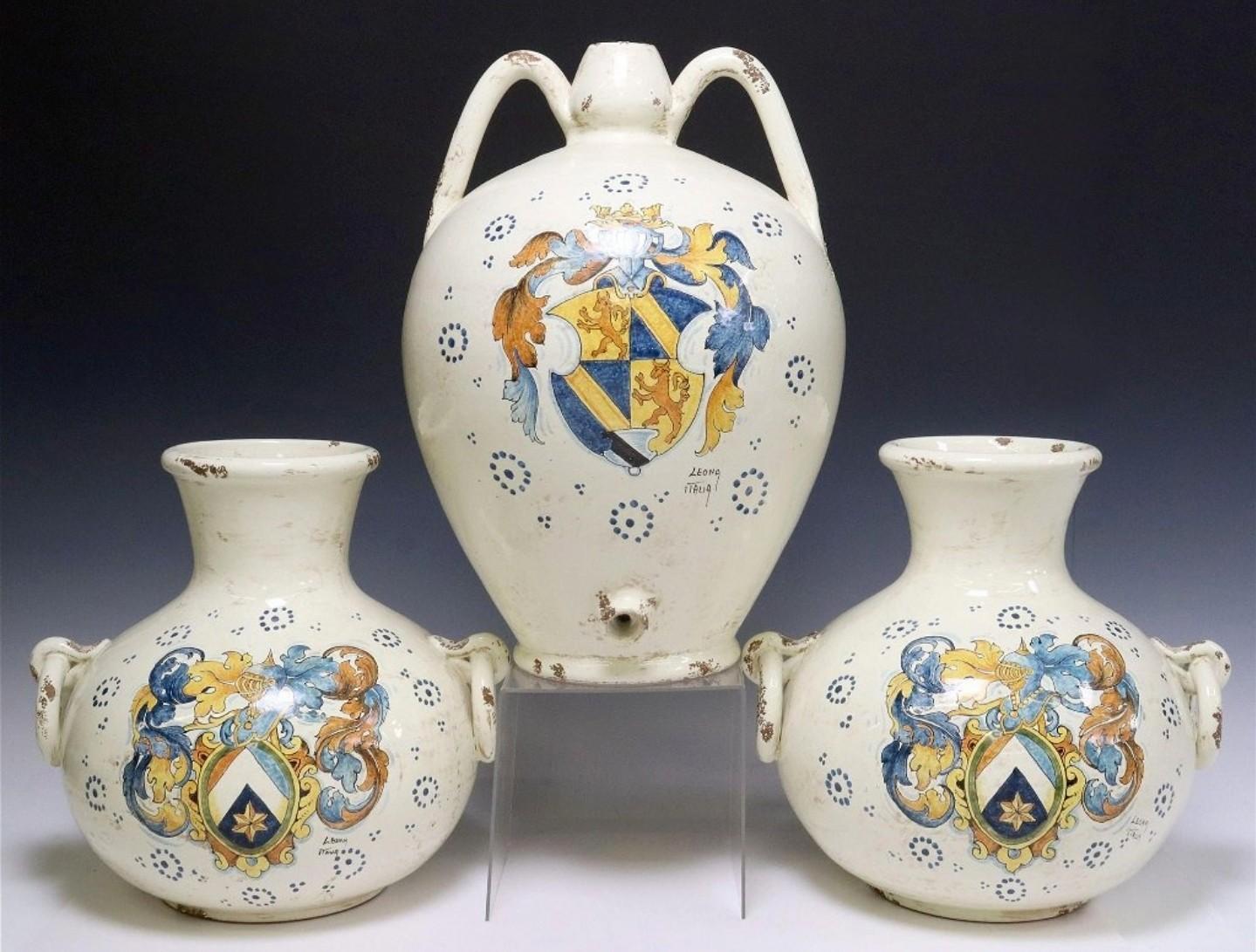 A vintage Italian majolica ceramic three piece vessel garniture set, signed Leona Italia.

Hand-crafted and hand-painted by highly skilled artisans in Tuscany, medieval Renaissance taste, each having hand painted coat of arms, varied designs, marked