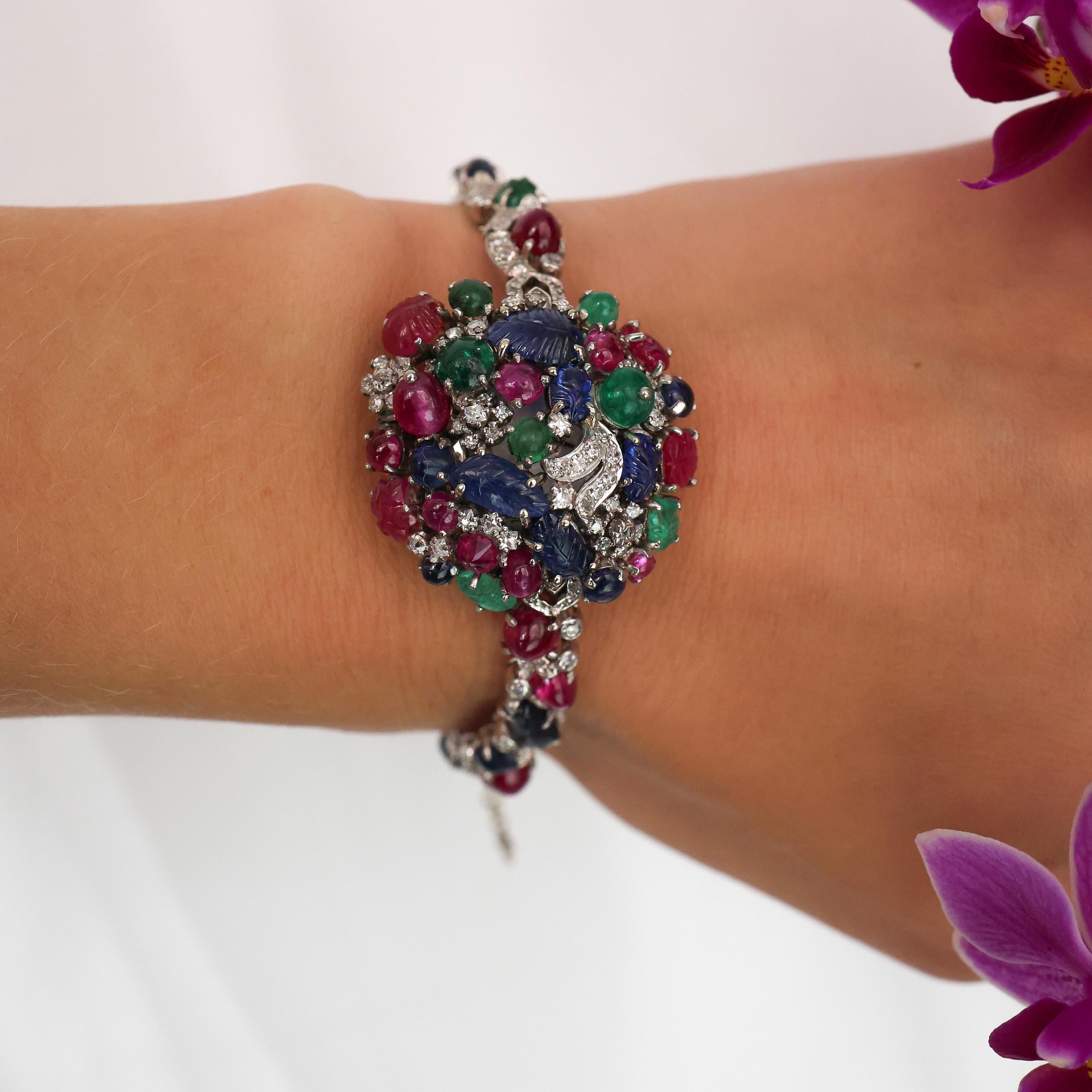An Art Deco tutti fruiti diamond, sapphire, ruby emerald and platinum cocktail covered watch, set with carved and cabochon-cut rubies, sapphires and emeralds, in claw settings, with eight-cut, square-cut round brilliant-cut and French-cut  diamonds