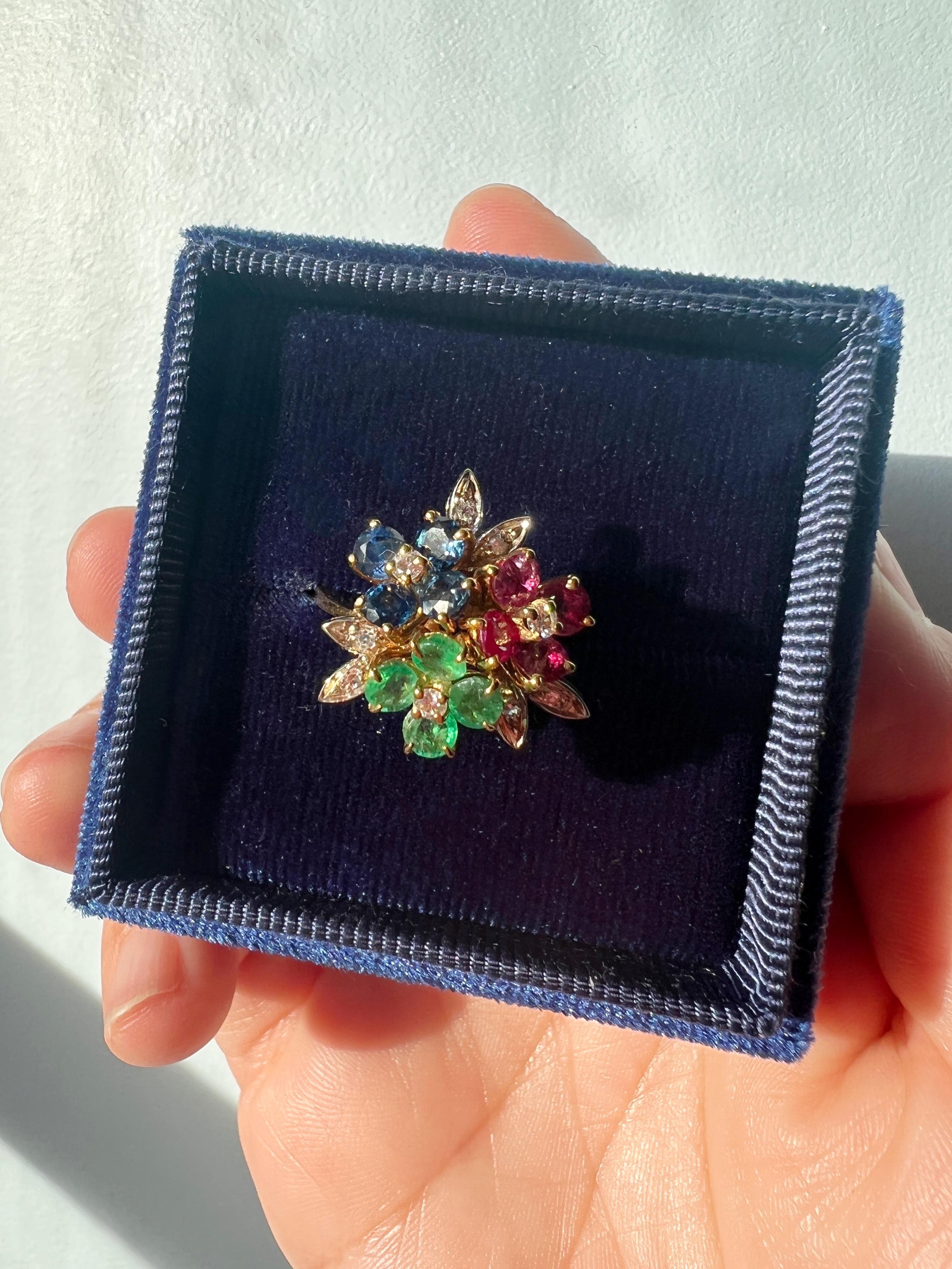 For sale a very beautiful vintage 18K yellow gold ring, featuring three flowers made in diamonds, blue sapphires, rubies and emeralds. Fresh, colorful and vibrant, the ring is inspired by the tropical wave that was to be the heyday of jewelry from
