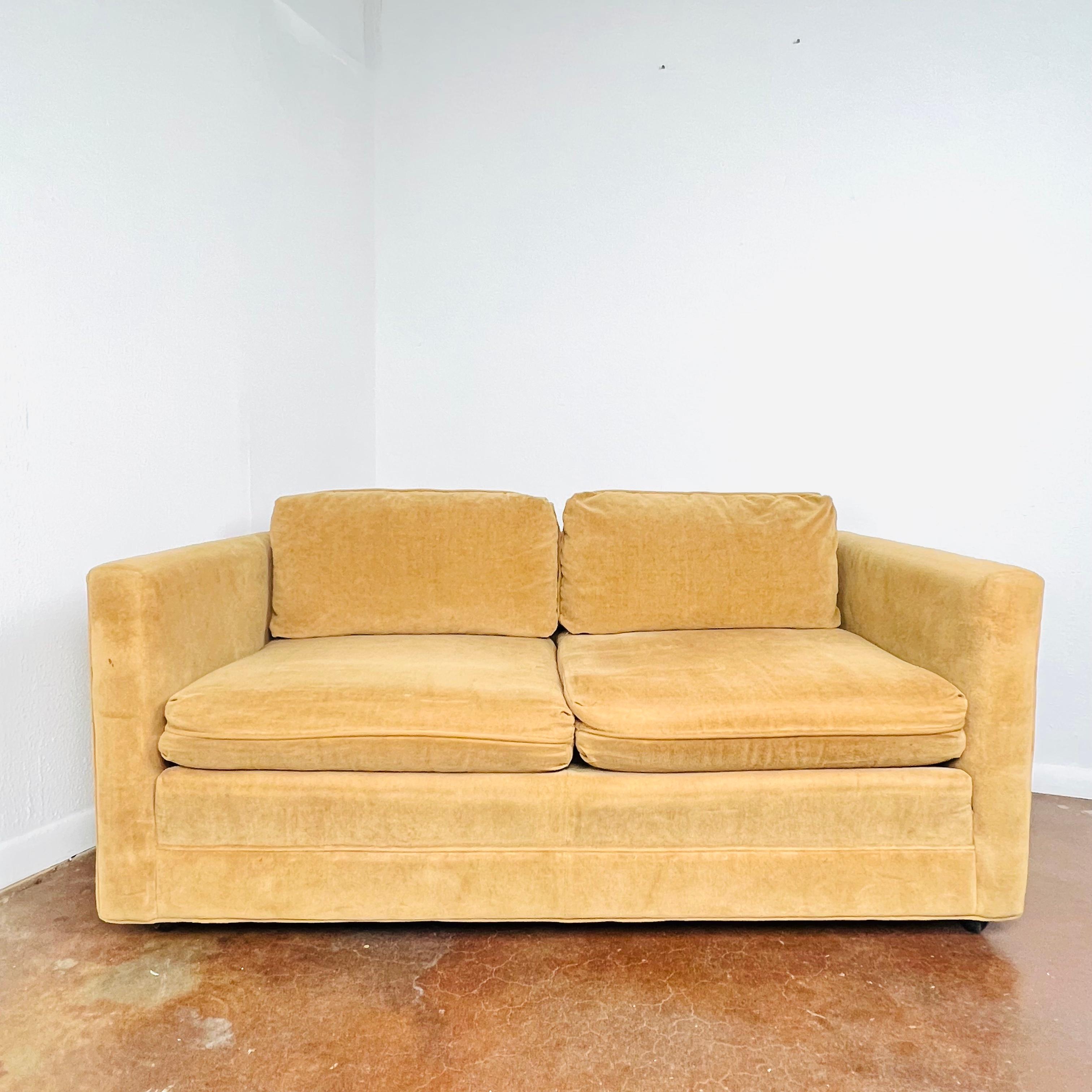 A Minimalist 1960s design, this Milo Baughman style tuxedo loveseat features a sturdy, streamlined frame with straight back and arms. Front casters. Upholstery shows some wear and discoloration; reupholstery is recommended.