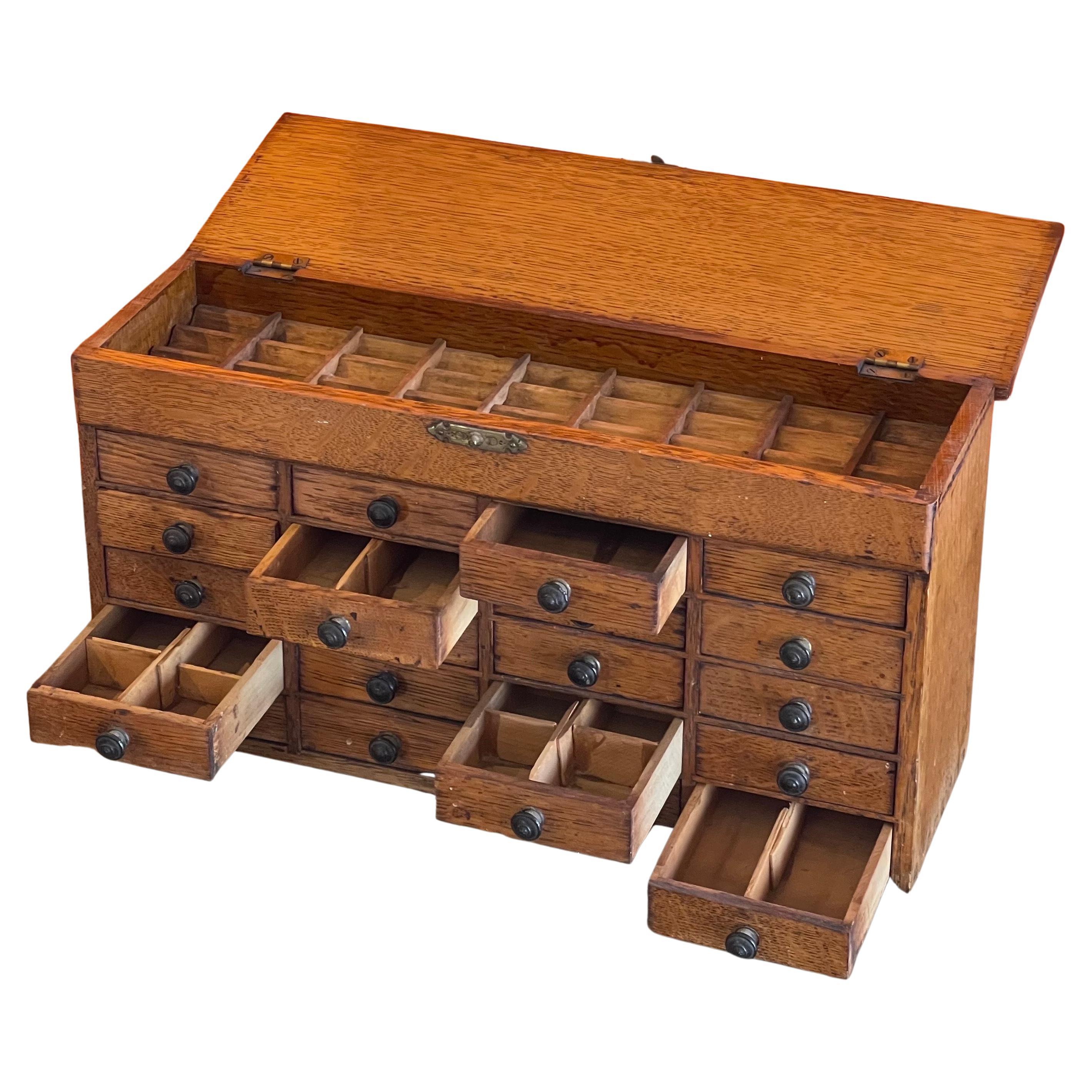 A very nice vintage twenty drawer oak watchmaker's chest / box / cabinet, circa 1950s. The piece is handmade out of oak and in good vintage condition; it is finished on all sides with brass hardware pulls and latch.  There are 20 small drawers with
