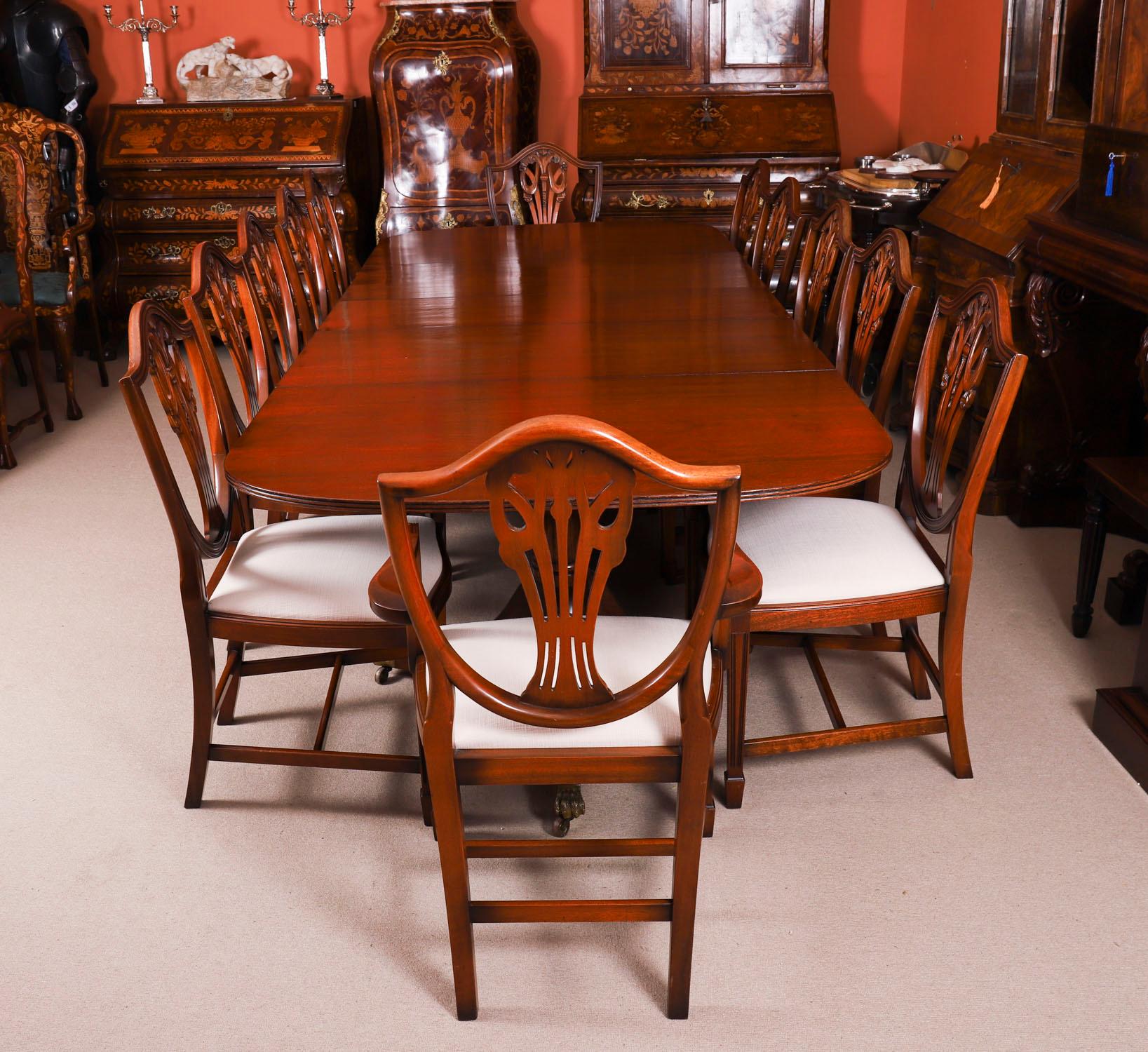 This is a superb large Vintage twin pedestal dining table in elegant George III style,  crafted in mahogany with twelve Hepplewhite Revival dining chairs, dating from the  mid 20th Century.

The table is capable of seating twelve people in regal