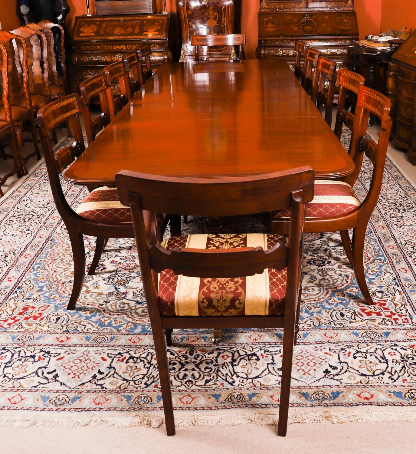 Il s'agit d'une superbe table de salle à manger Vintage à deux pieds, dans l'élégant style George III, fabriquée en acajou avec douze chaises de salle à manger Regency Revival, datant du milieu du 20ème siècle.

La table peut accueillir douze