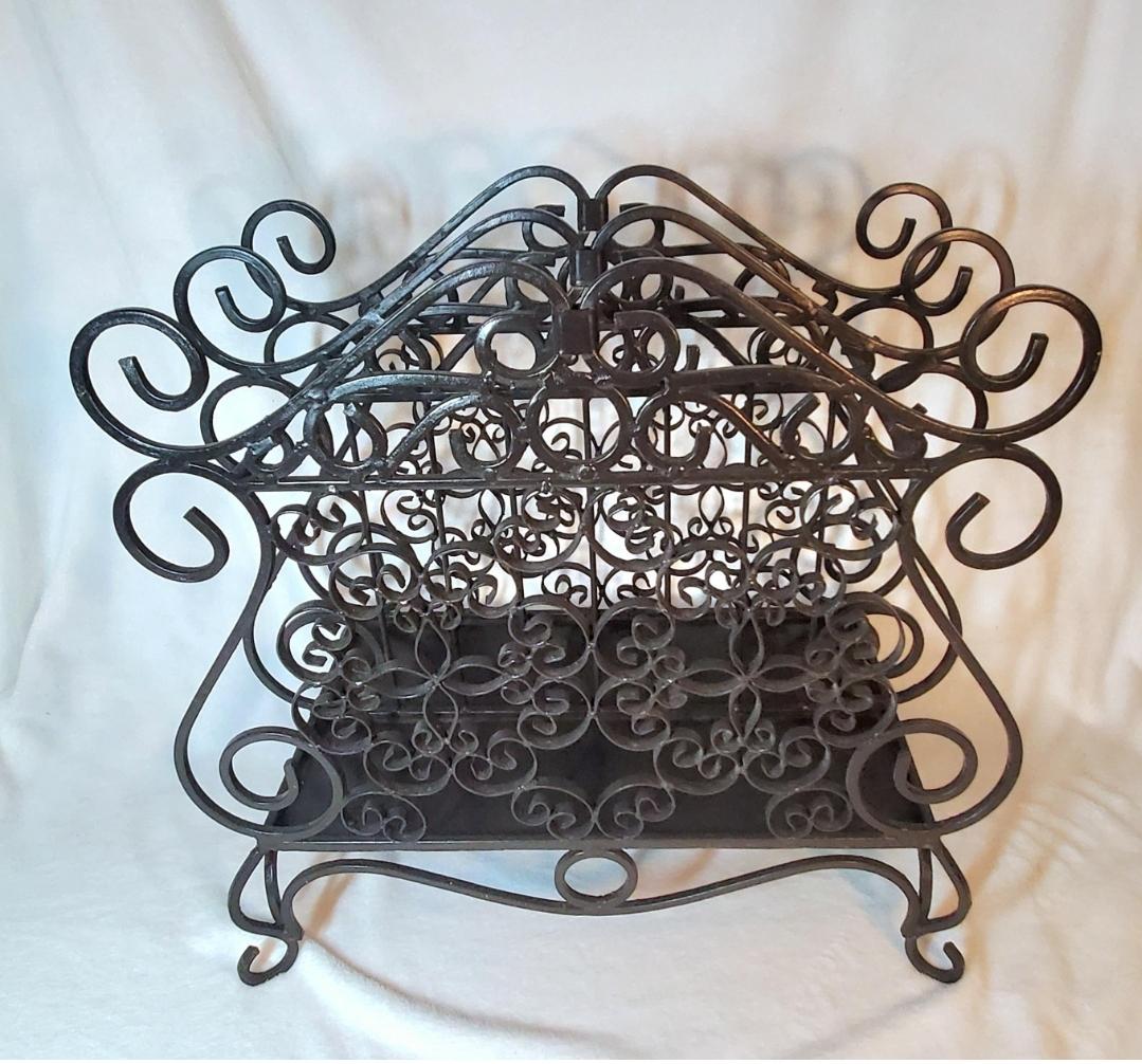 Heavy.
Solid.
Twisted wrought iron.
Can hold books, magazines, records.
4 well balanced legs.