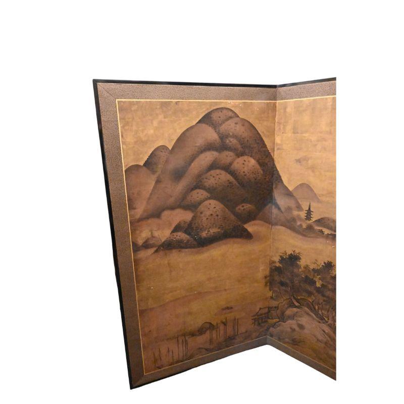 A vintage two panel Asian screen with a watercolor landscape with a gold leaf sky, that effortlessly transports you to a realm of tranquil beauty. This masterfully crafted piece captures the essence of a majestic mountainous scene, adorned by a sky