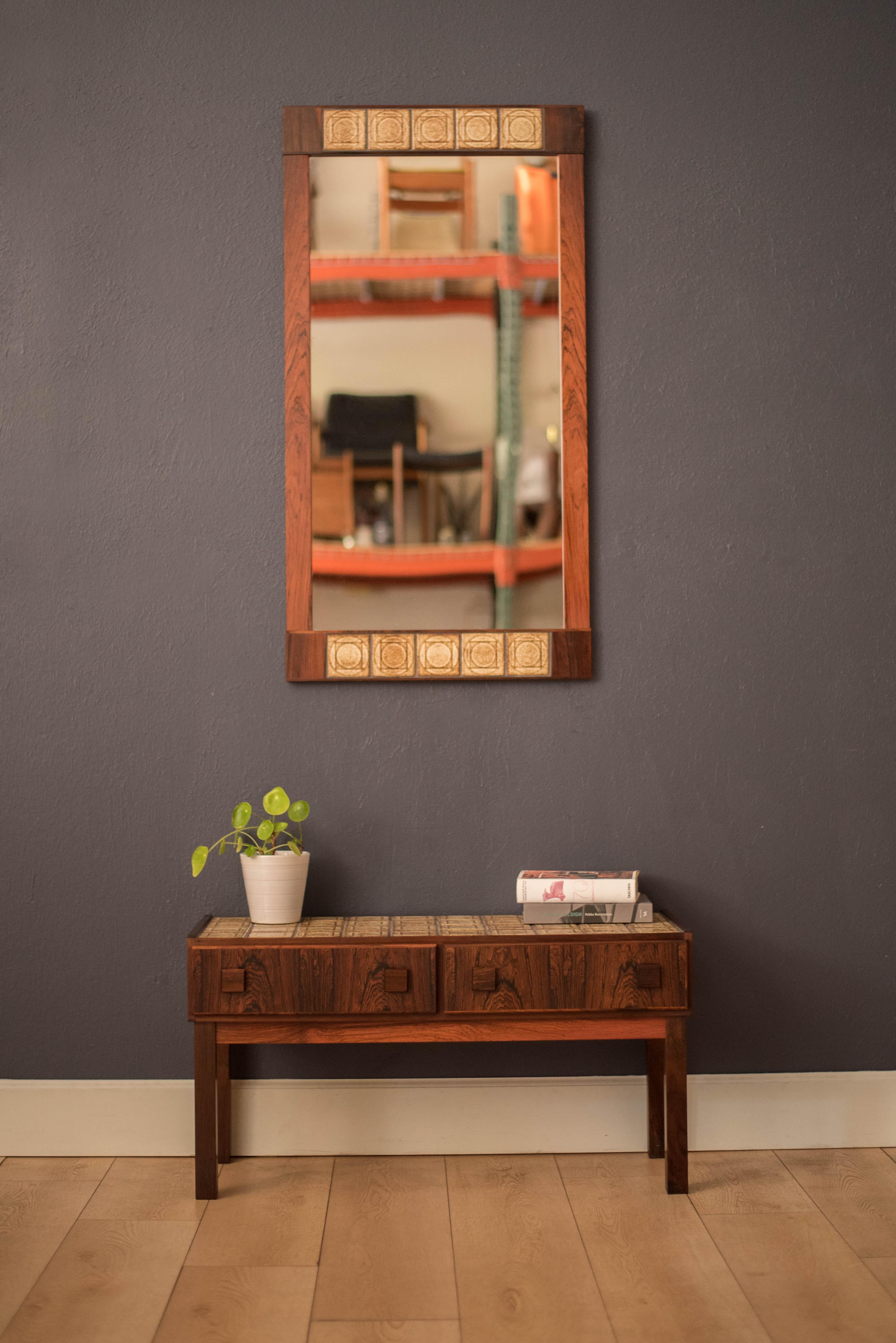 Mid-Century Modern two piece entryway cabinet and hanging wall mirror in rosewood, circa 1970s, Denmark. This set features natural rosewood grains accented with a unique ceramic tile inlay. Provides storage including two drawers crafted with square