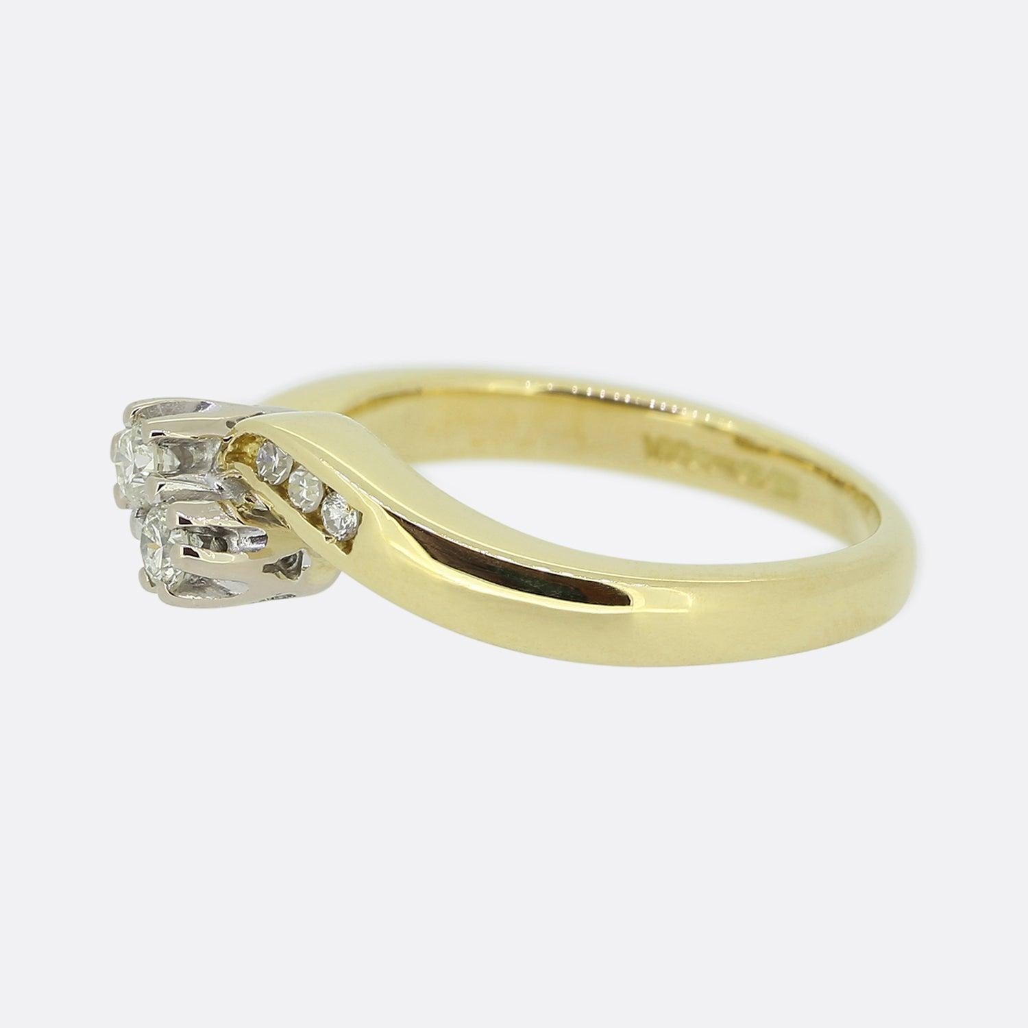 Here we have a classic two-stone diamond ring. This vintage piece has been crafted from 18ct yellow gold and showcases a duo of closely claw set round brilliant cut diamonds in a diagonal fashion. A swirling band acts as the backdrop to these