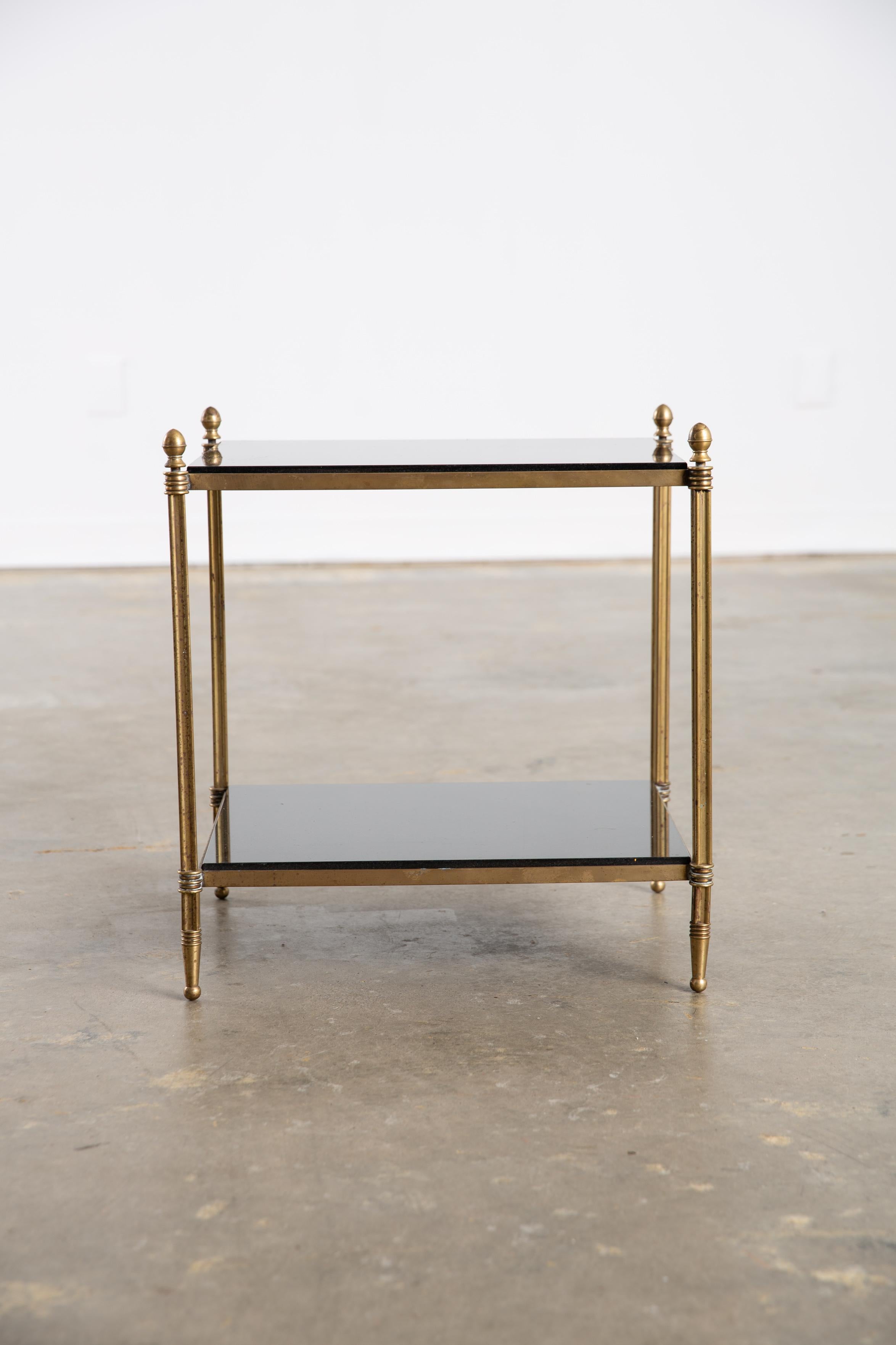 Table d'appoint vintage à deux niveaux en laiton et pierre noire avec détails de finitions et détails décoratifs. Très bonne patine du laiton. Repose sur de petits pieds en boule. 