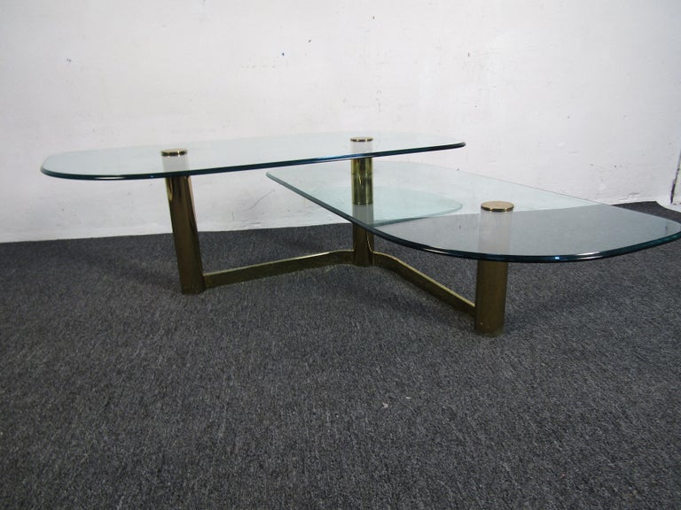 Unusual vintage coffee table with two tiers of glass tabletops, and a brass base. Sure to be a nice addition to any modern interior. Please confirm item location.