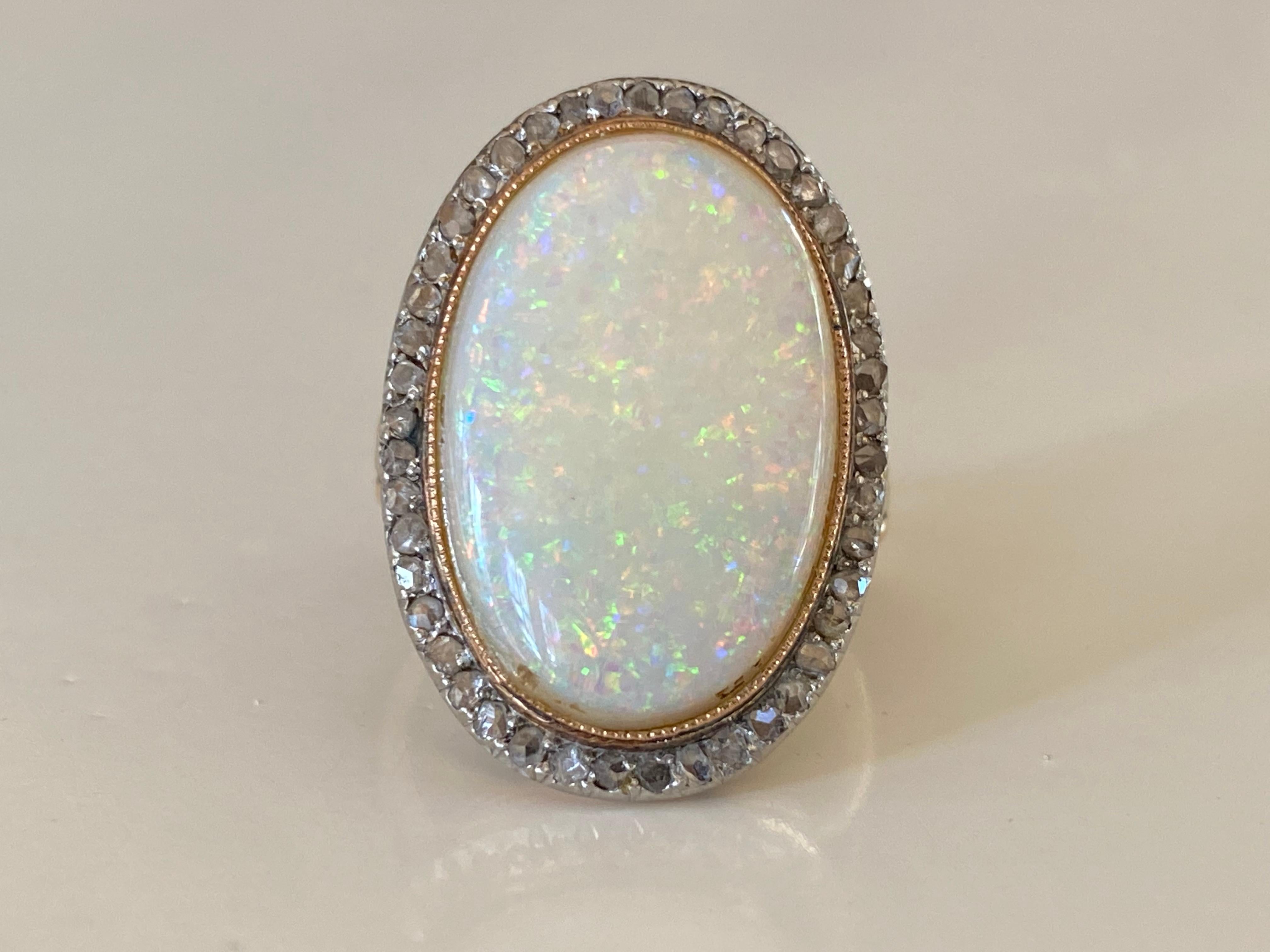 Crafted in the 1930s in 18kt yellow gold and platinum, this two-tone vintage cocktail ring features a natural oval-shaped Australian opal cabochon with a multi-color 