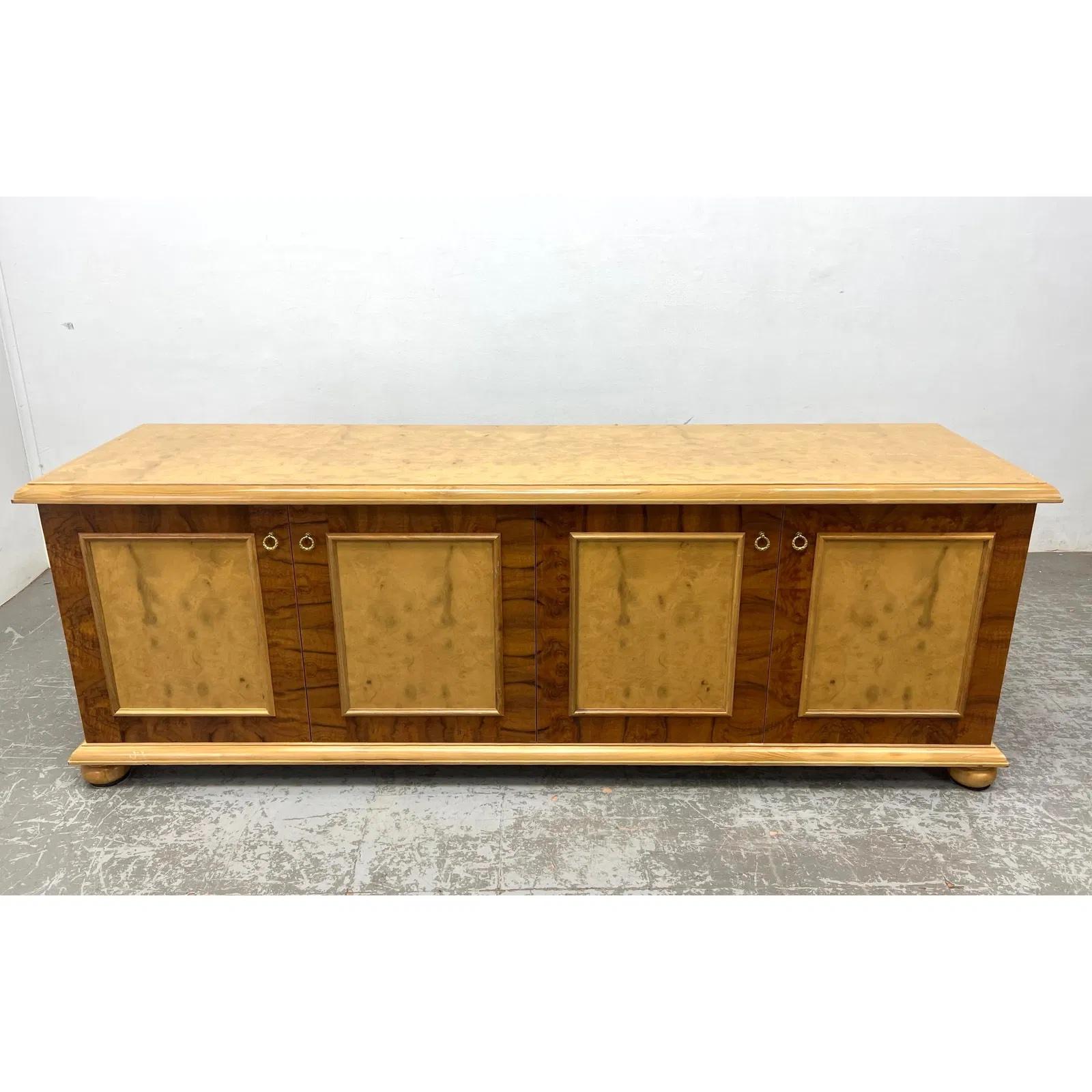 Aparador de 4 puertas de diseño bicolor con paneles de chapa de madera burl y marco de madera clara. Este versátil mueble, con sus clásicas patas en forma de bollo y herrajes de anilla, ofrece un amplio espacio de almacenamiento para utilizarlo como