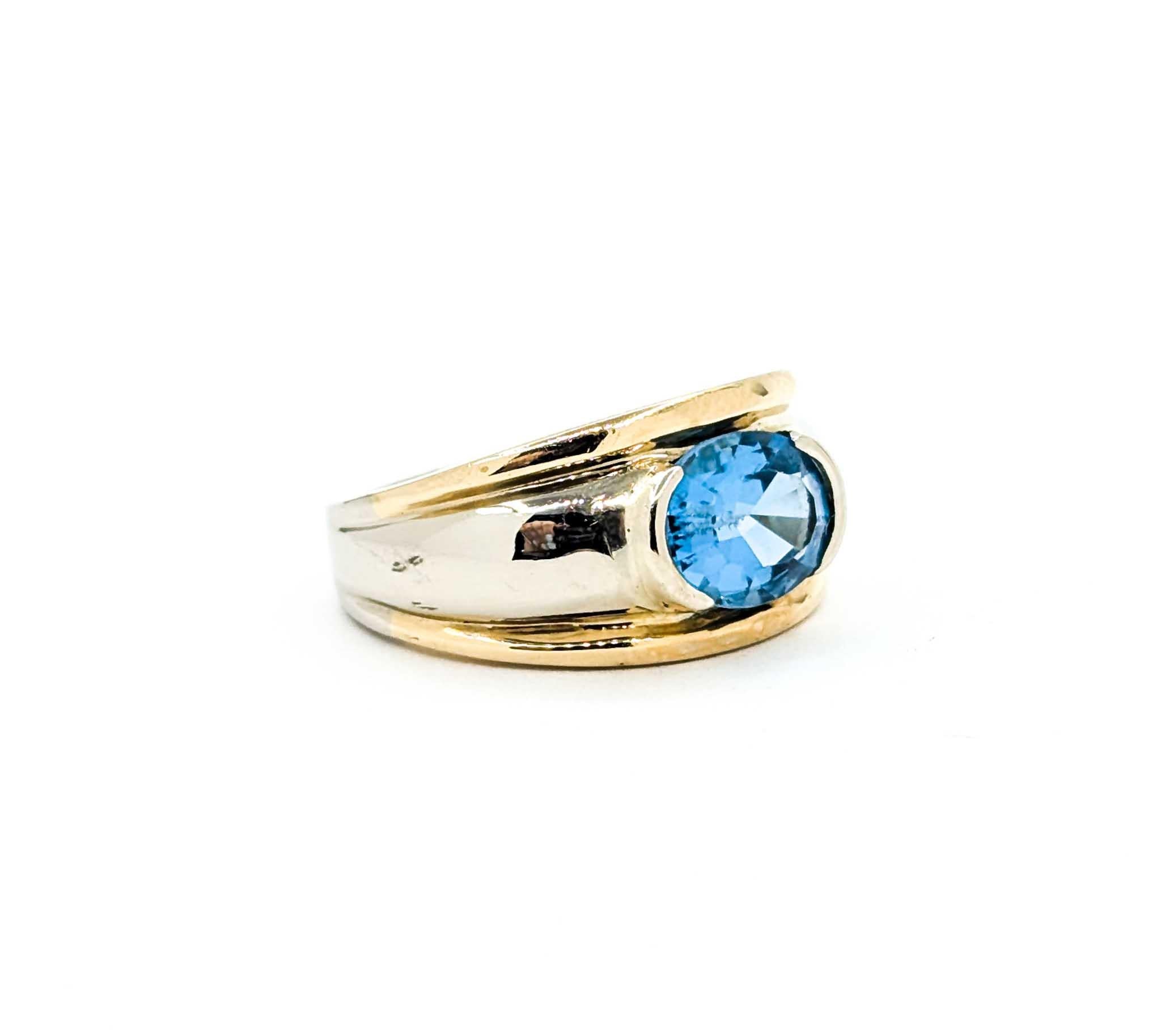 This bold vintage ring features a vivid 2.30 carat Swiss blue topaz, bezel-set in a sleek two-tone 14k gold design. The oval-cut topaz displays a bright, saturated sky-blue hue, perfectly complemented by the warm yellow gold borders and cool white
