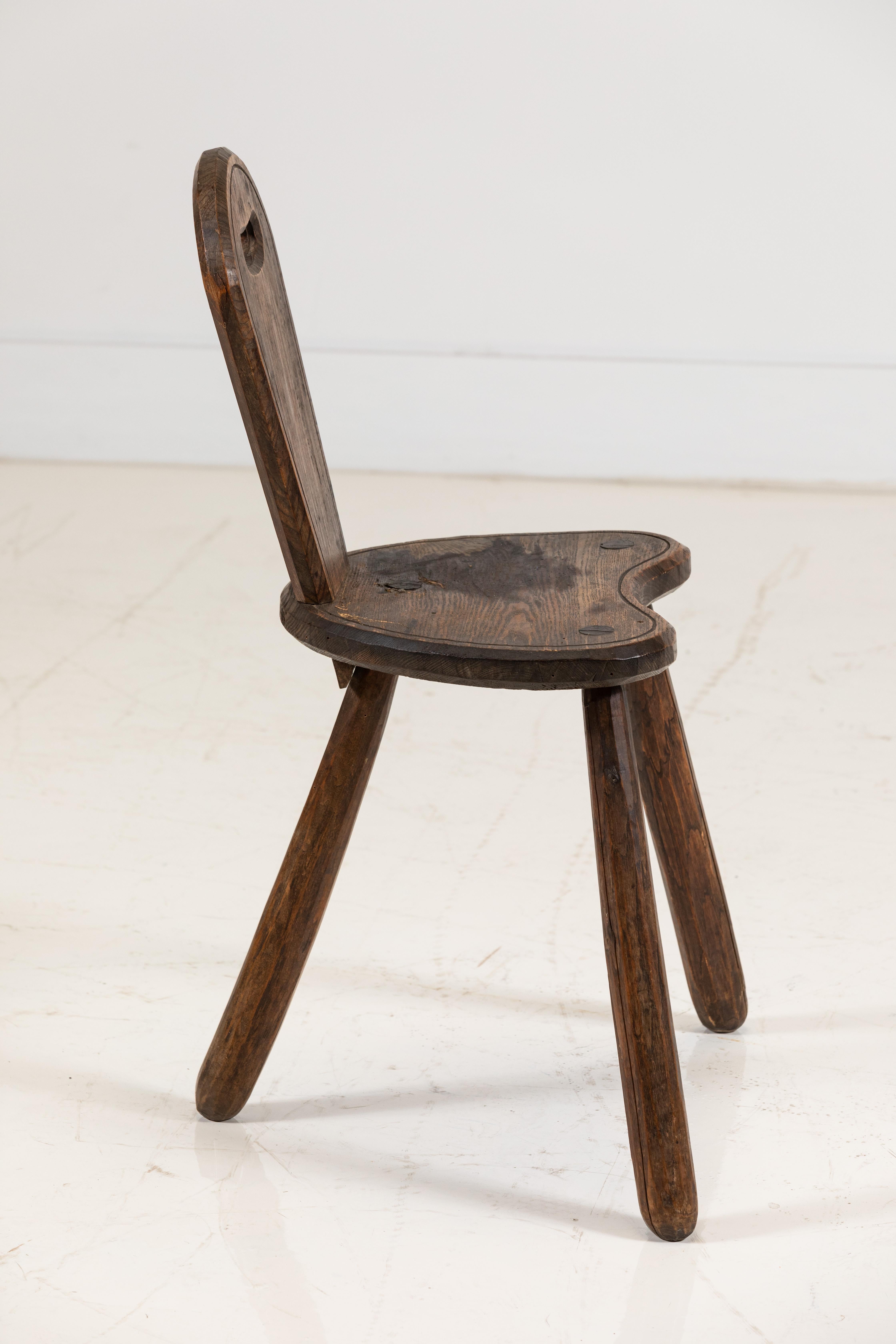 Unique wooden chair with three legs and a single back panel. The chair has an Austrian Tyrolean Classic style.