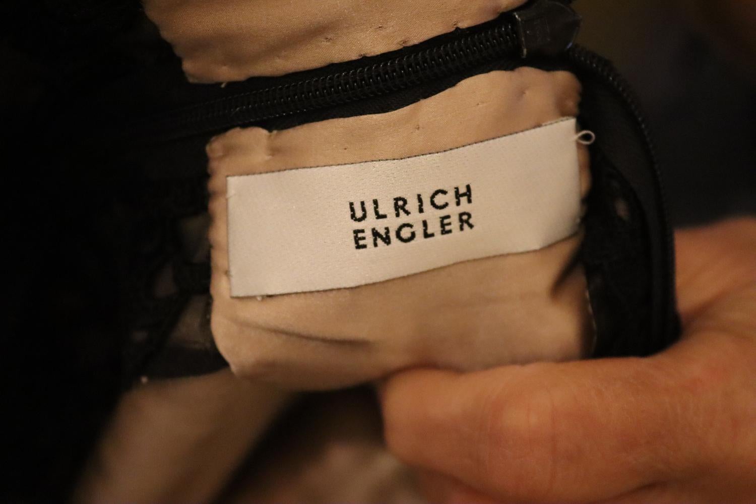 A stunning black lace couture dress by Ulrich Engler. The dress is lined in silk, and has a contrasting waist band.  It  has elbow length sleaves, a back zip opening, scoop neckline and 8'' slit at the back. It has the original silk shoulder pads,