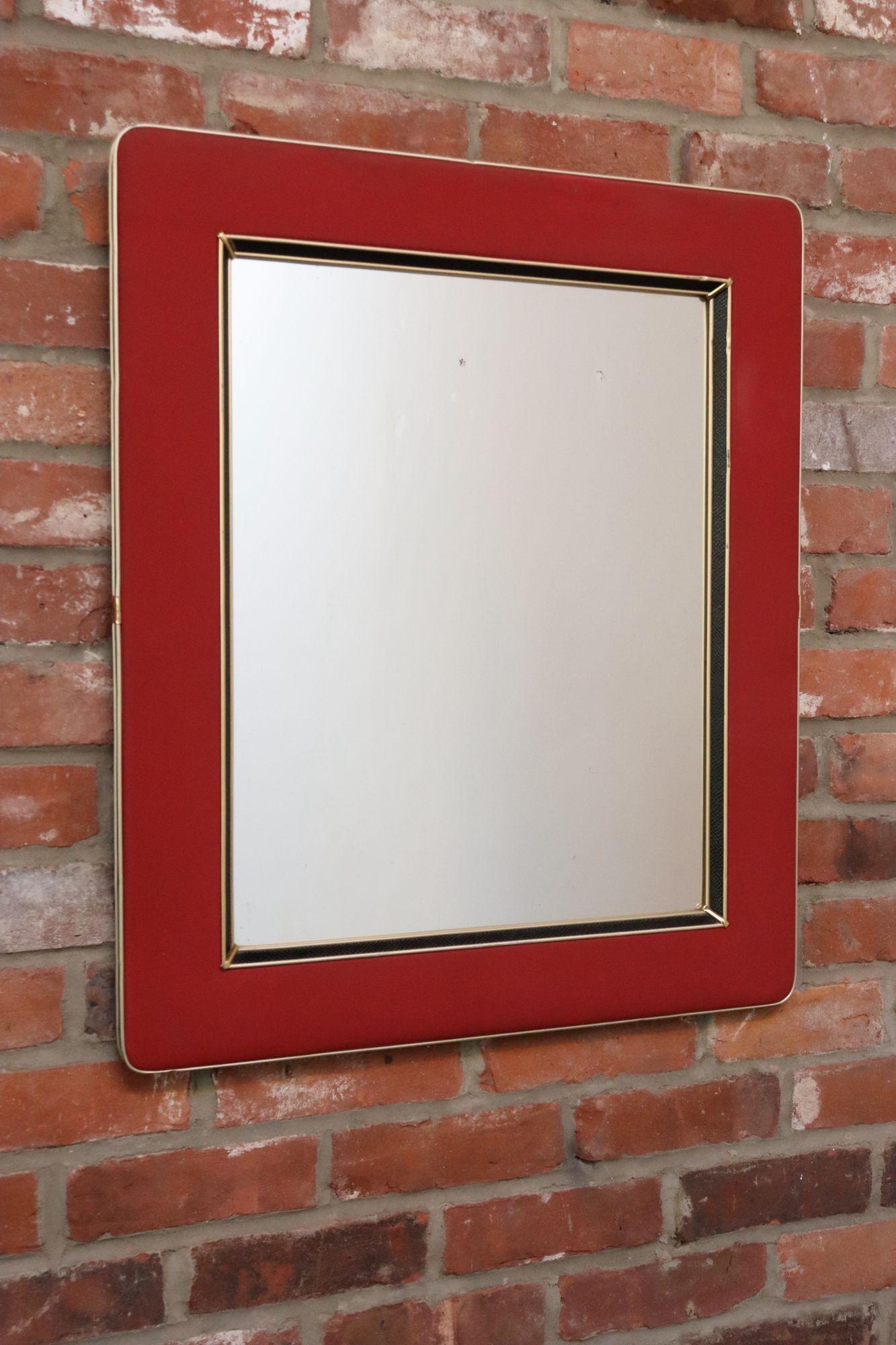 Specchio da parete vintage disegnato da Umberto Mascagni (ca. anni '50, Italia).
È composta da una struttura in legno avvolta da un rivestimento sintetico rosso lampone simile al vinile, con finiture interne e laterali in pelle nera e