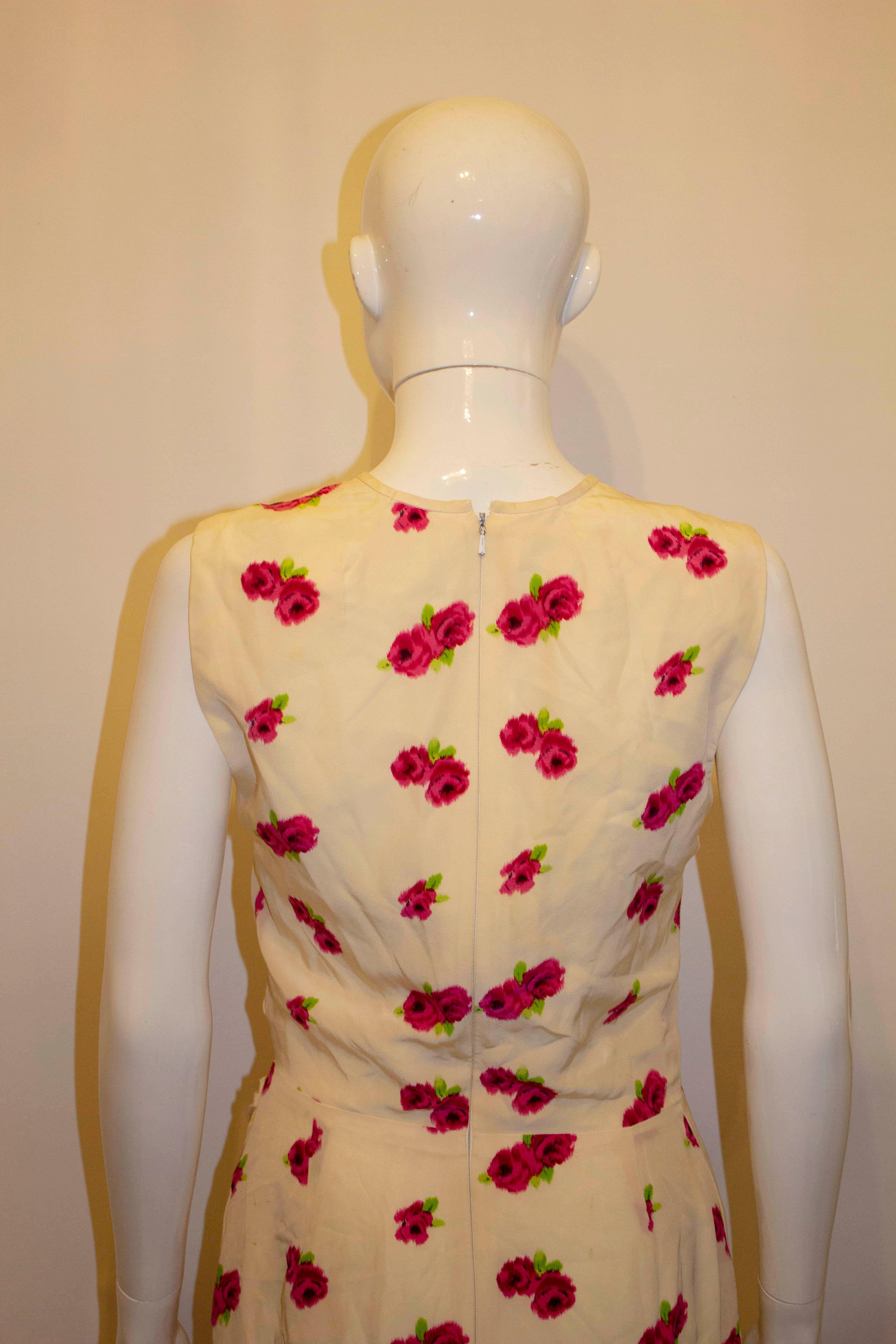 A stunning vintage silk dress by Ungaro. The dress has a white background, with a pink and green floral print, and gathering on the left hand side. The dress is lined and has a back central zip opening. Size 46 /12. Measurements : Bust 36'', length