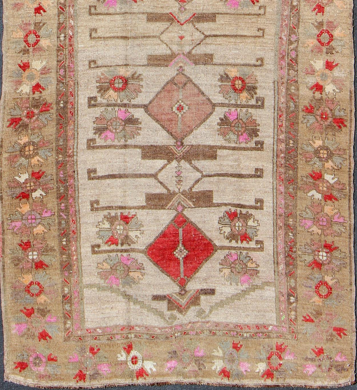 Vintage Turkish runner in red, pink, beige, tan, green, bright lavender, taupe, rug tu-ugu-4809, country of origin / type: Turkey / Oushak, circa 1950

This vintage runner features an assortment of tribal designs and flowers throughout its center