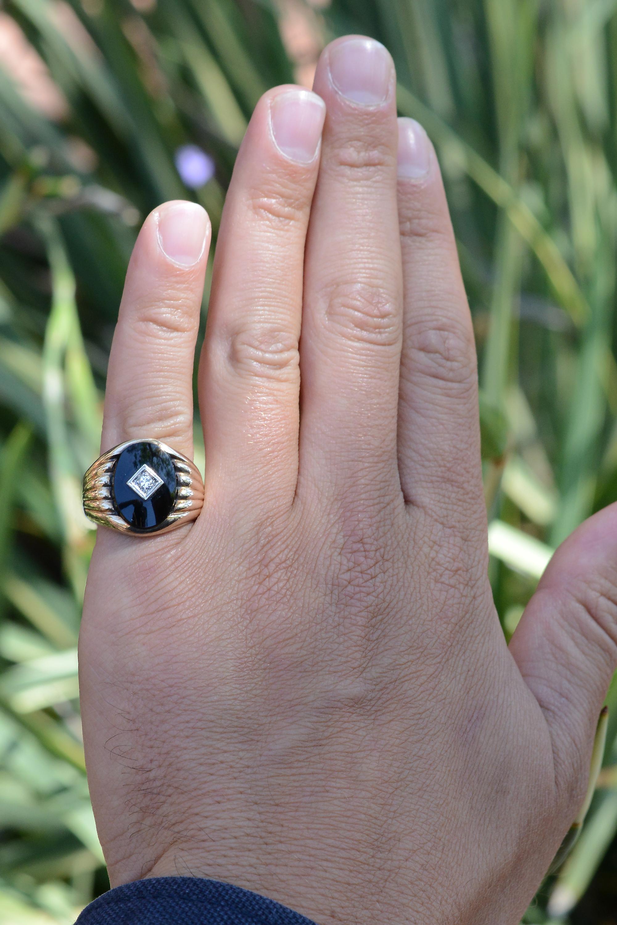 A classic vintage estate unisex black onyx and diamond cocktail ring. A fiery round brilliant diamond peers out from a skillfully polished oval onyx, excellently paired with a rich yellow gold band. The ring is both affordable and sustainable and