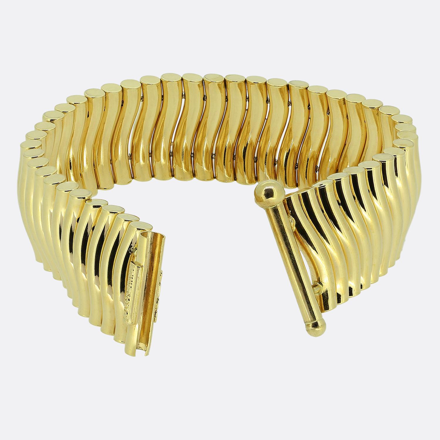 Aquí tenemos una llamativa pulsera del estimado diseñador UnoAErre. Fabricada en oro amarillo de 18 quilates, esta pieza presenta una serie de eslabones elegantemente curvados que crean un patrón ondulado y fluido. El diseño es atrevido y