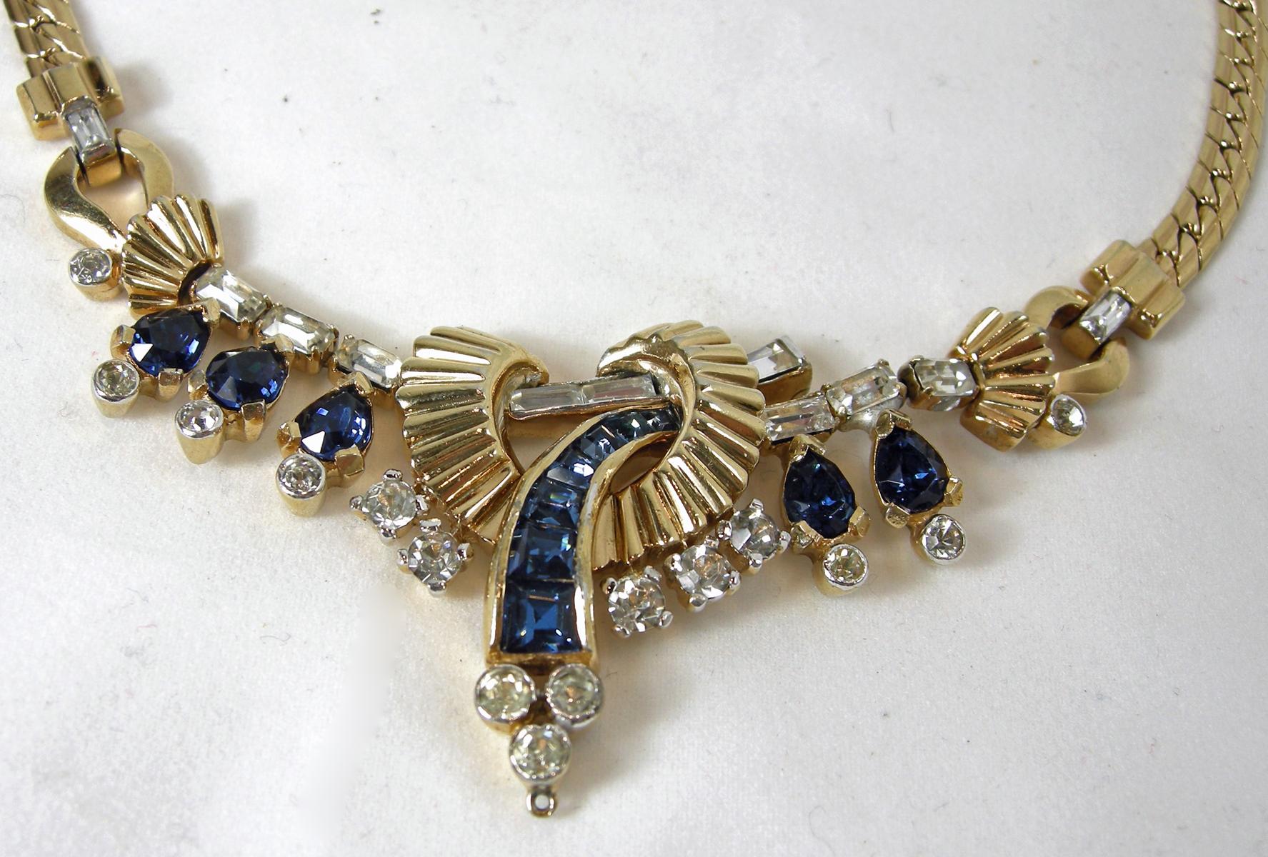 Although this necklace is not signed, I know this is a vintage Mazer necklace.   It has a fold-over clasp connected to a gold tone chain leading down to the beautiful centerpiece.  The center has baguette crystals and going through a ribbed circle.