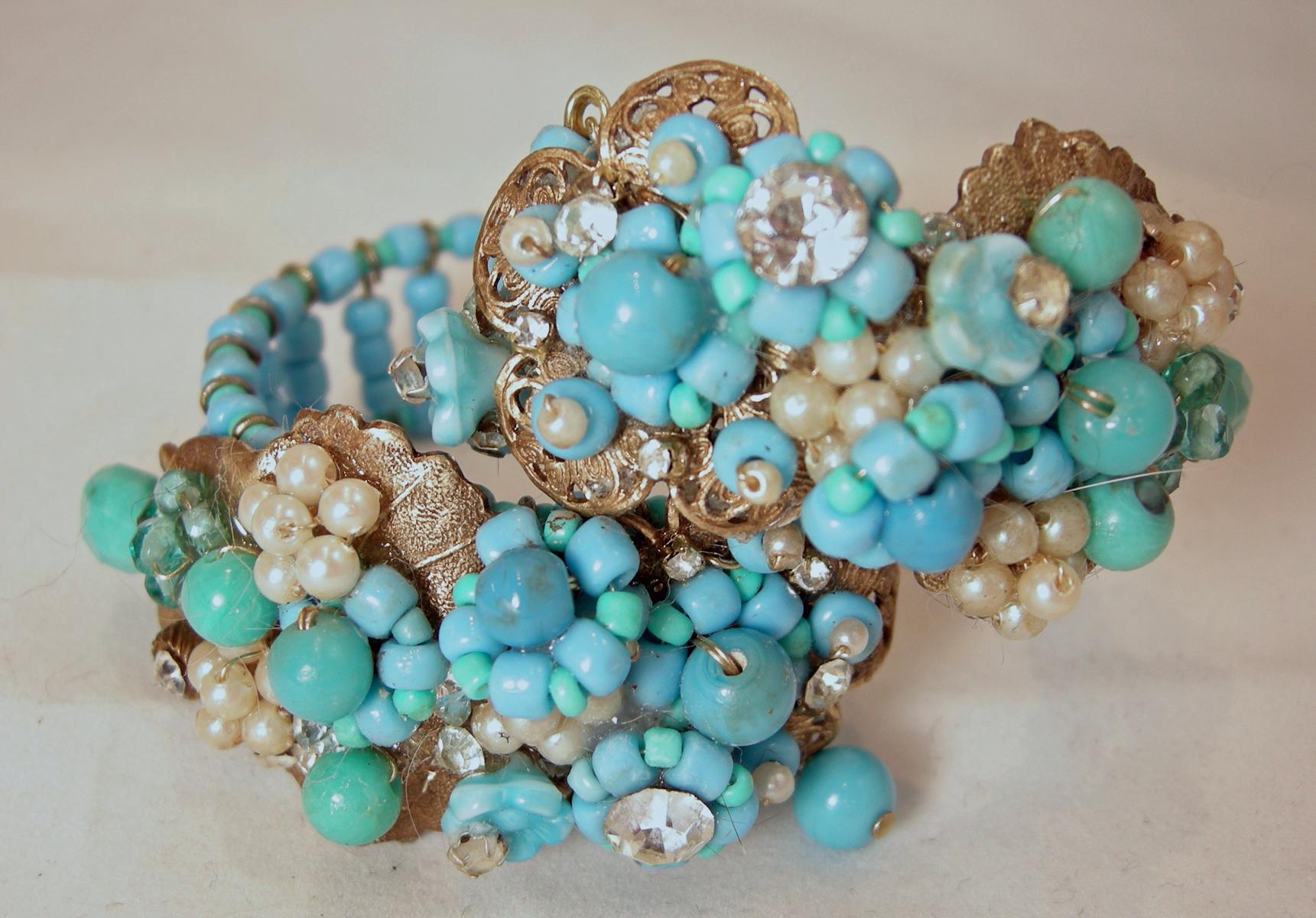 This vintage unsigned Haskell wrap bracelet has a floral design on both sides with faux turquoise flowers mixed with faux pearl flowers and crystal accents … set on a gold tone filigree base. In excellent condition, this wrap bracelet measures