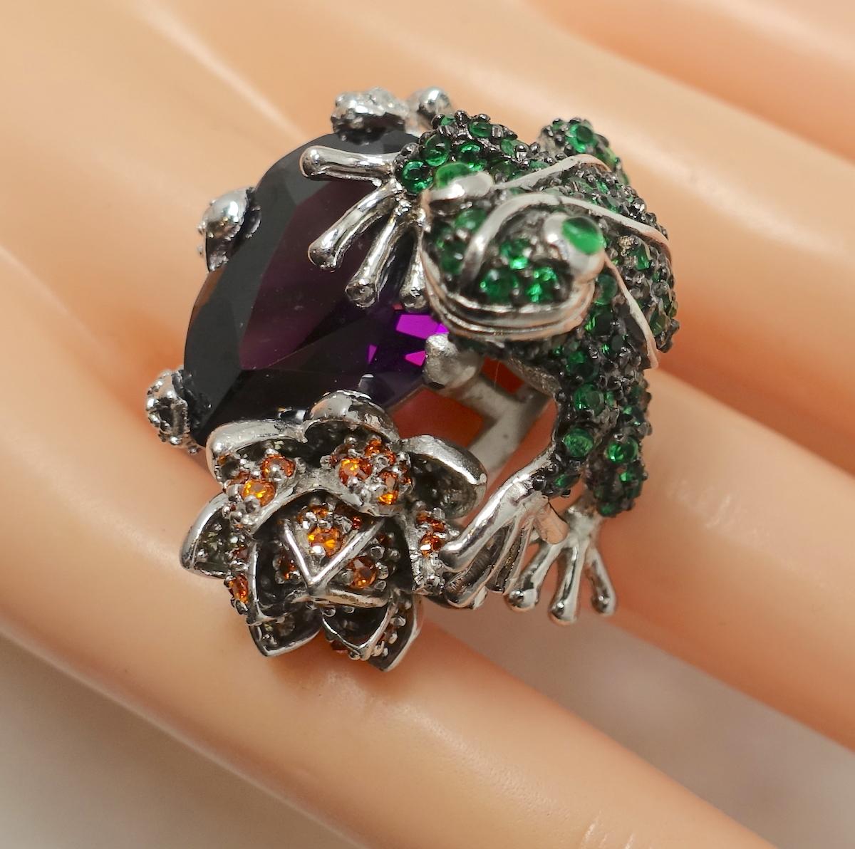This vintage ring has an unusual frog design with large amethyst crystal and accents of green and red crystals in a sterling silver setting.  A size 7+, this ring measures 1-1/4” x 1”.