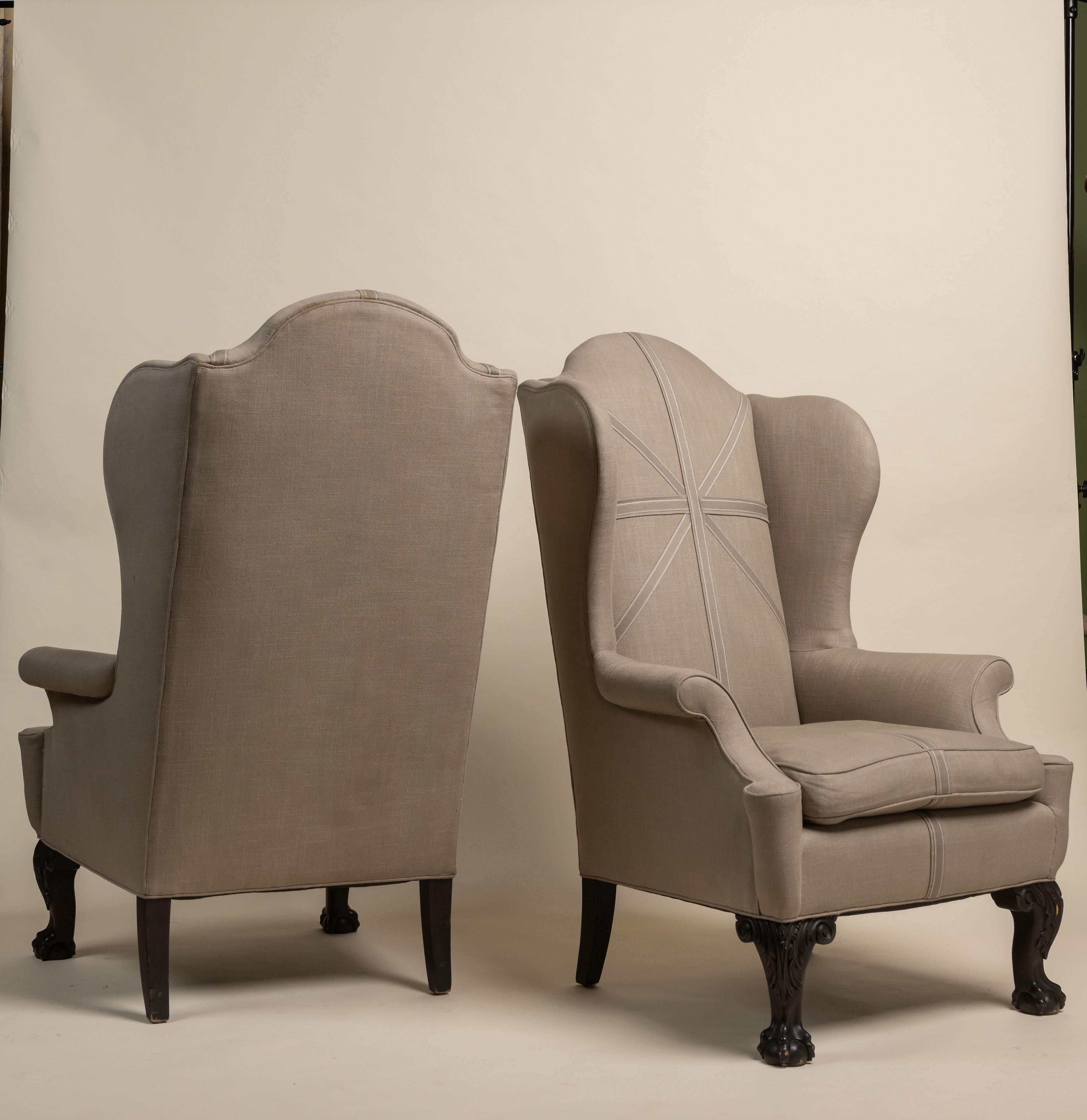 Late 18th century American Chippendale wingback chairs are recently upholstered and trimmed. These chairs are known for their high backs, and 