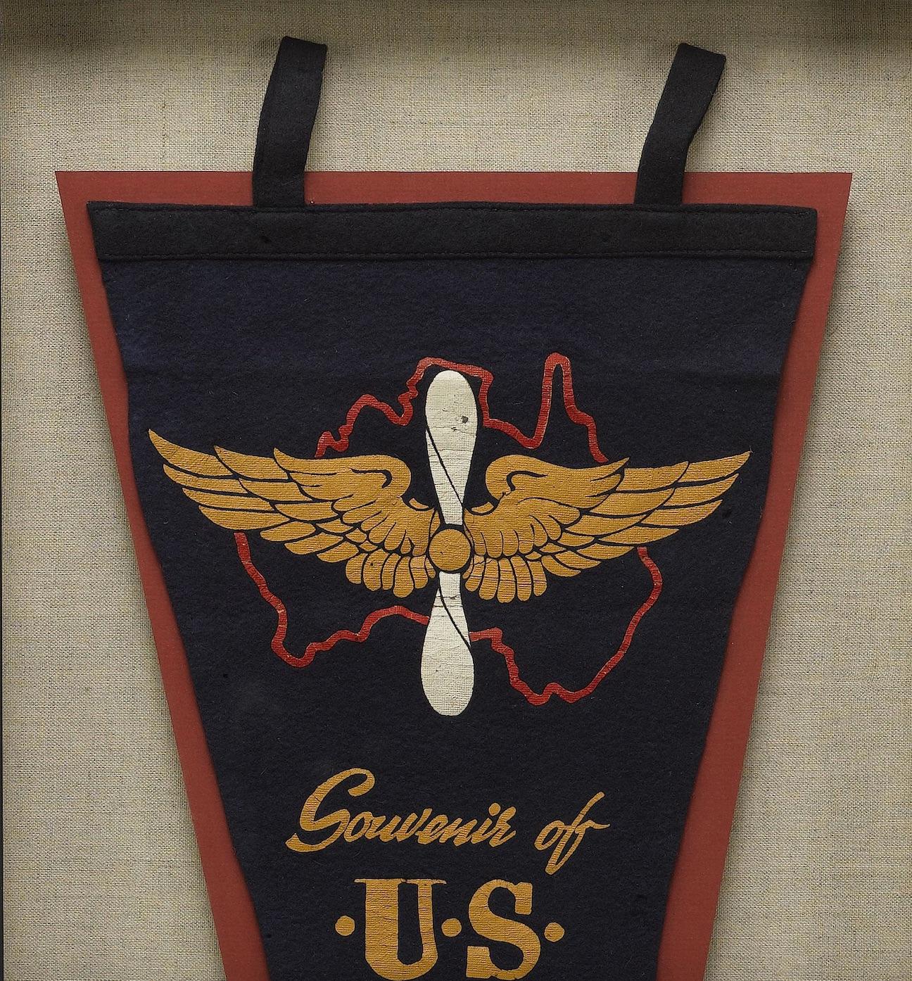 Presented is a souvenir felt pennant celebrating the servicemen and women of the U.S. Air Corps who were based in Australia and fought alongside members of the Royal Australian Air Force during WWII. The navy pennant features a printed red outline