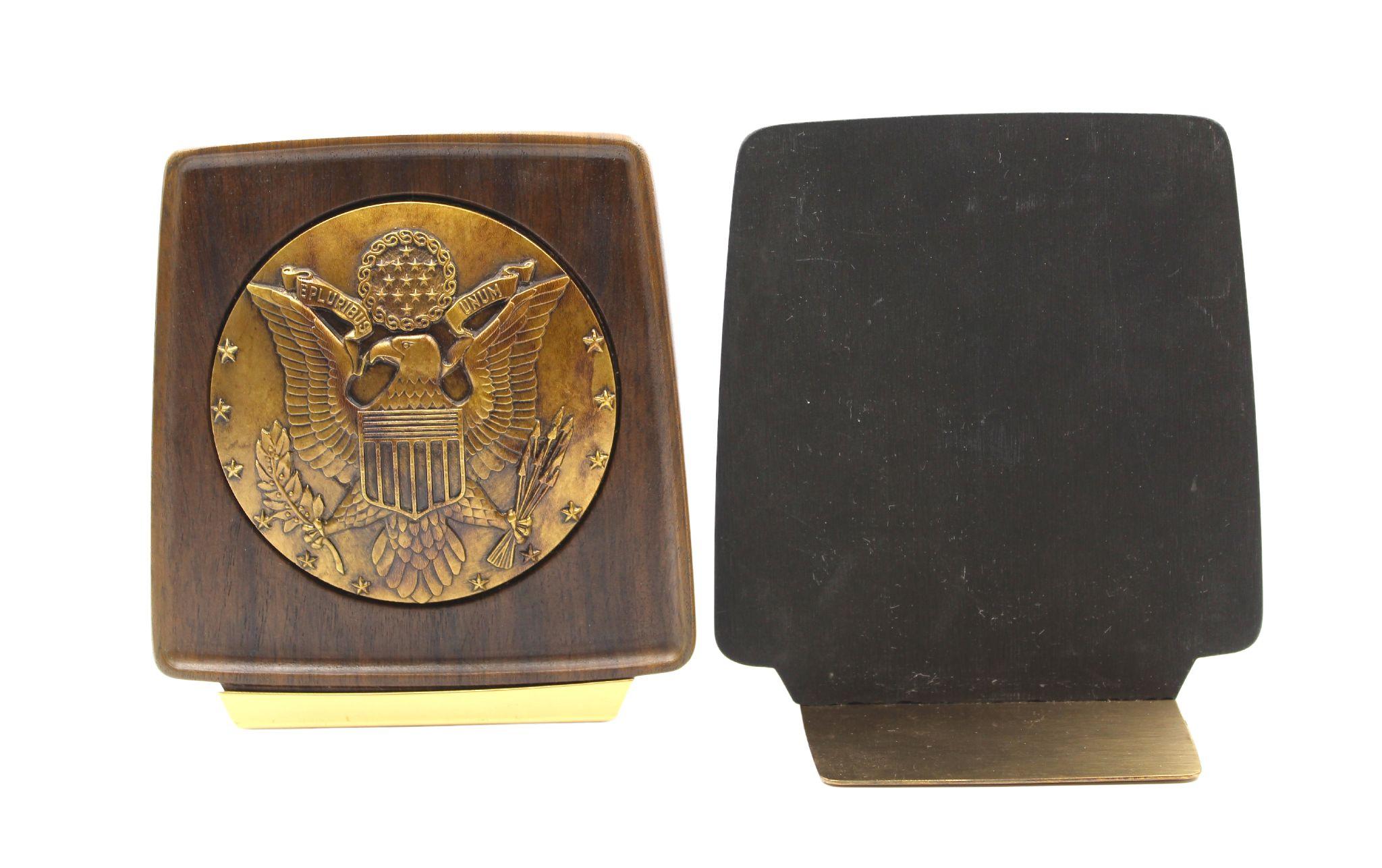 Presented is a pair of vintage U.S. Great Seal bookends. The bookends feature a brass-colored, raised relief U.S. Great Seal at center. The round seal is encased in a rich, walnut-toned resin, with slightly rounded corners and slim brass base. 

The
