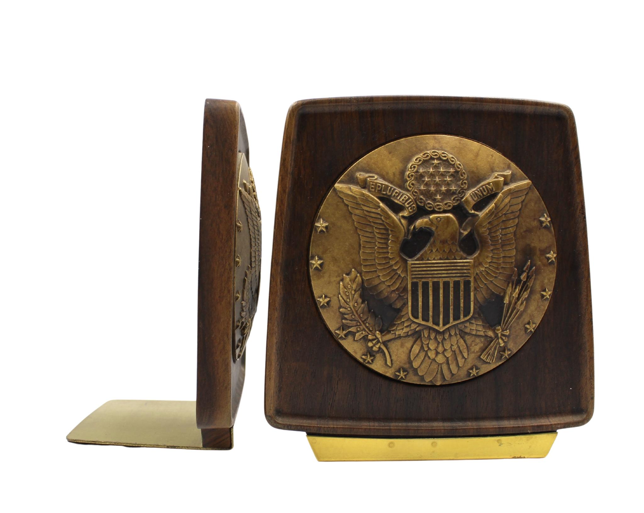 Presented is a pair of vintage U.S. Great Seal bookends, dating to the 1950s. The bookends feature a brass-colored, raised relief U.S. Great Seal at center. The round seal is encased in a rich, walnut-toned resin, with slightly rounded corners and
