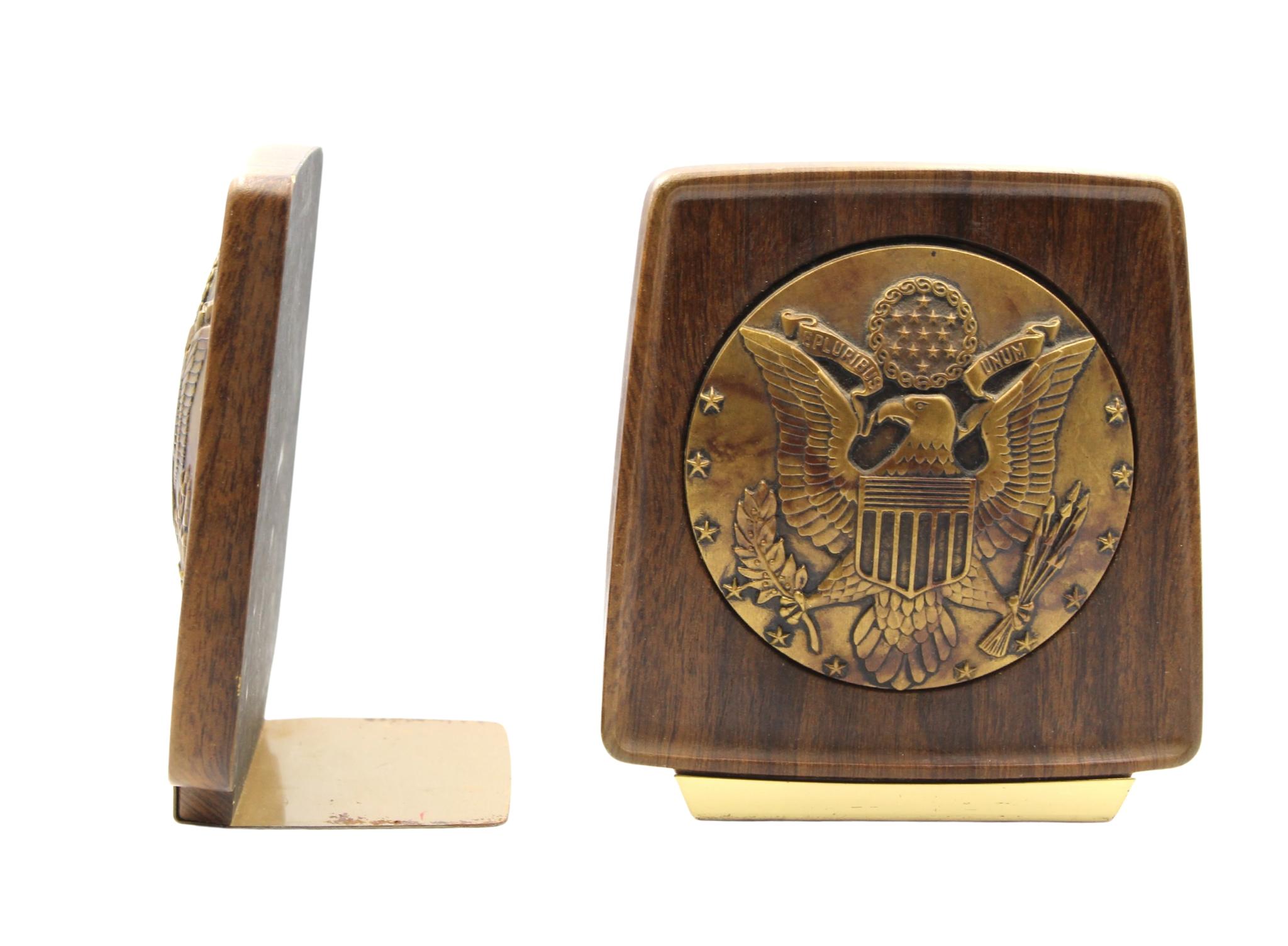 Presented is a pair of vintage U.S. Great Seal bookends, dating to the 1950s. The bookends feature a brass-colored, raised relief U.S. Great Seal at center. The round seal is encased in a rich, walnut-toned resin, with slightly rounded corners and