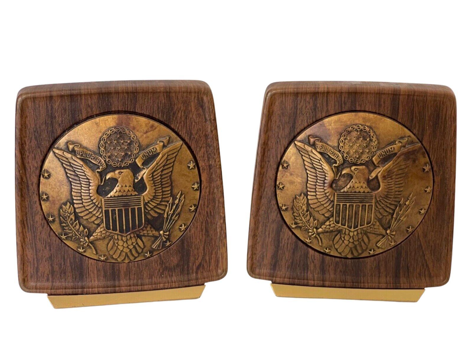 Presented is a pair of vintage U.S. Great Seal brass and wooden bookends. The bookends feature a brass, raised relief U.S. Great Seal at center. The round seal is encased in a rich, walnut-toned wood, with slightly rounded corners and slim brass