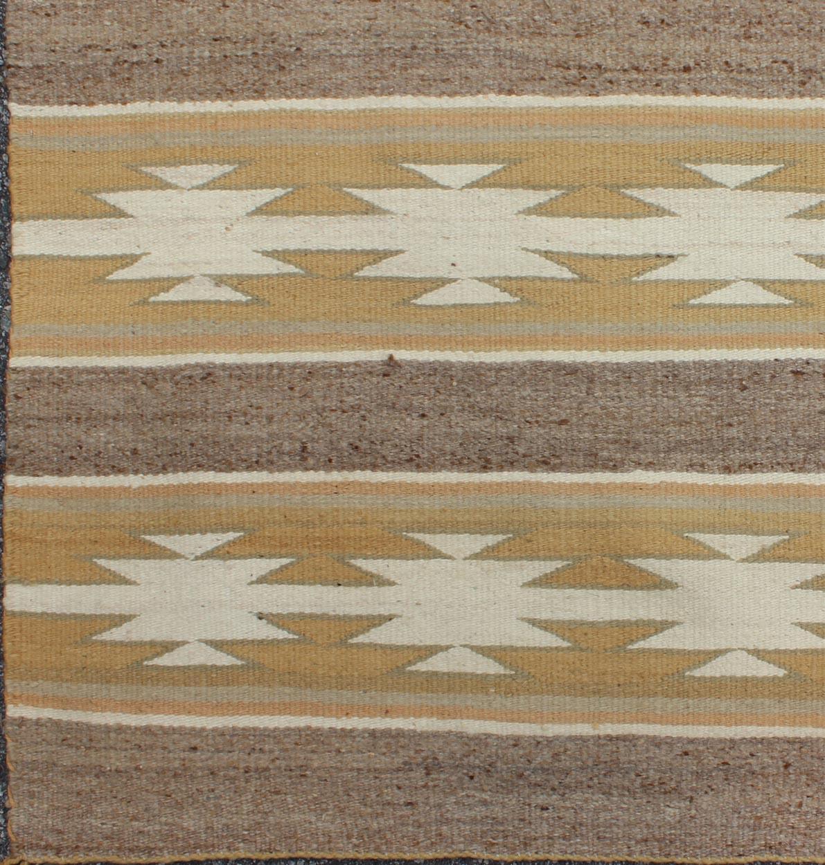 This intriguing antique Navajo Kilim, circa 1950 was woven in the United States during the mid-20th century. The exciting and unique composition boasts a captivating geometric composition with an all-over cross-shaped design. The range of colors