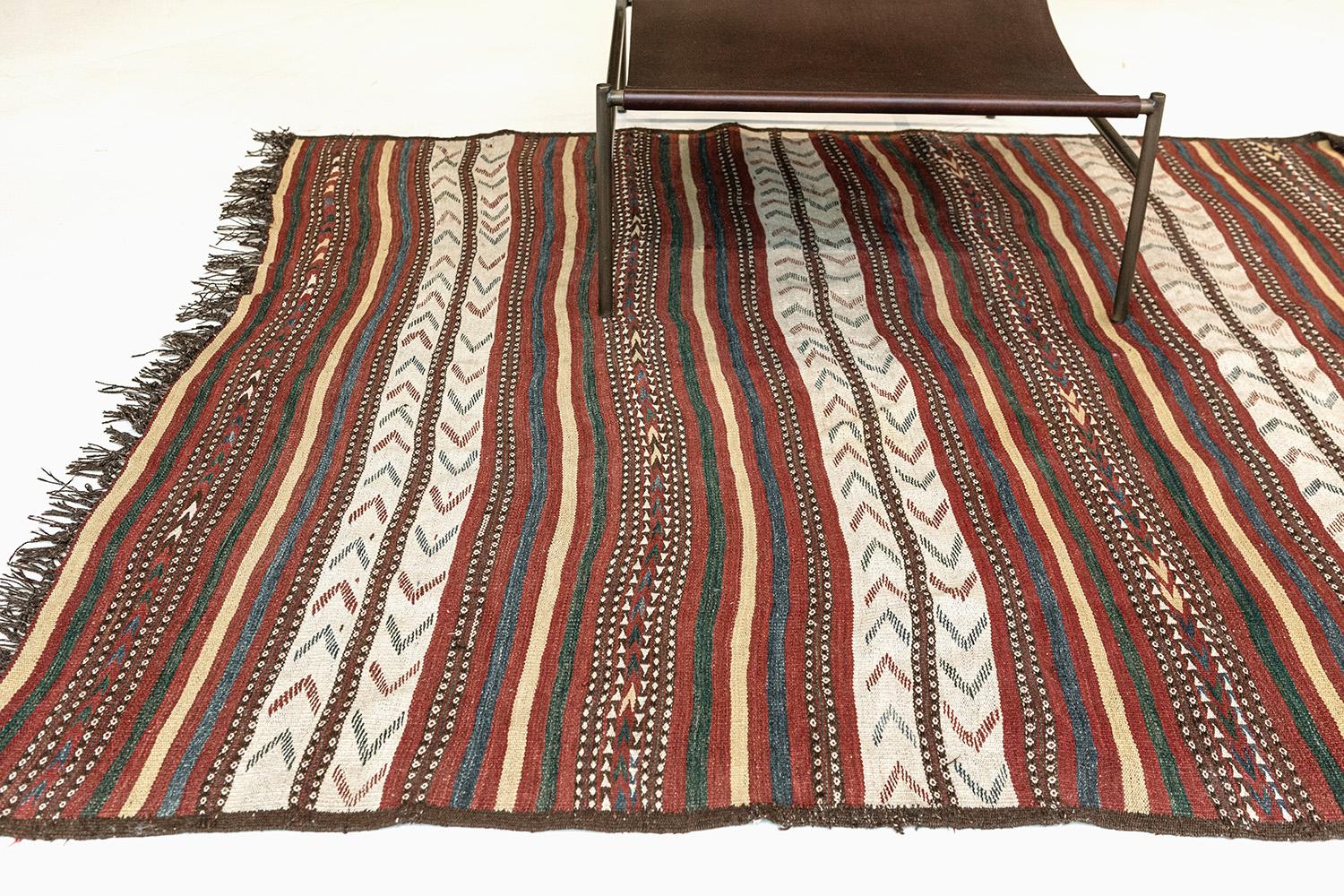 A handspun wool Uzbek Kilim stunned by double-arrowed motifs, divided with zig-zap stripes, and alternating chevrons into all-natural dyed vibrant colors. All fringes on the side are meticulously sewn and matches with the primitive texture and rich