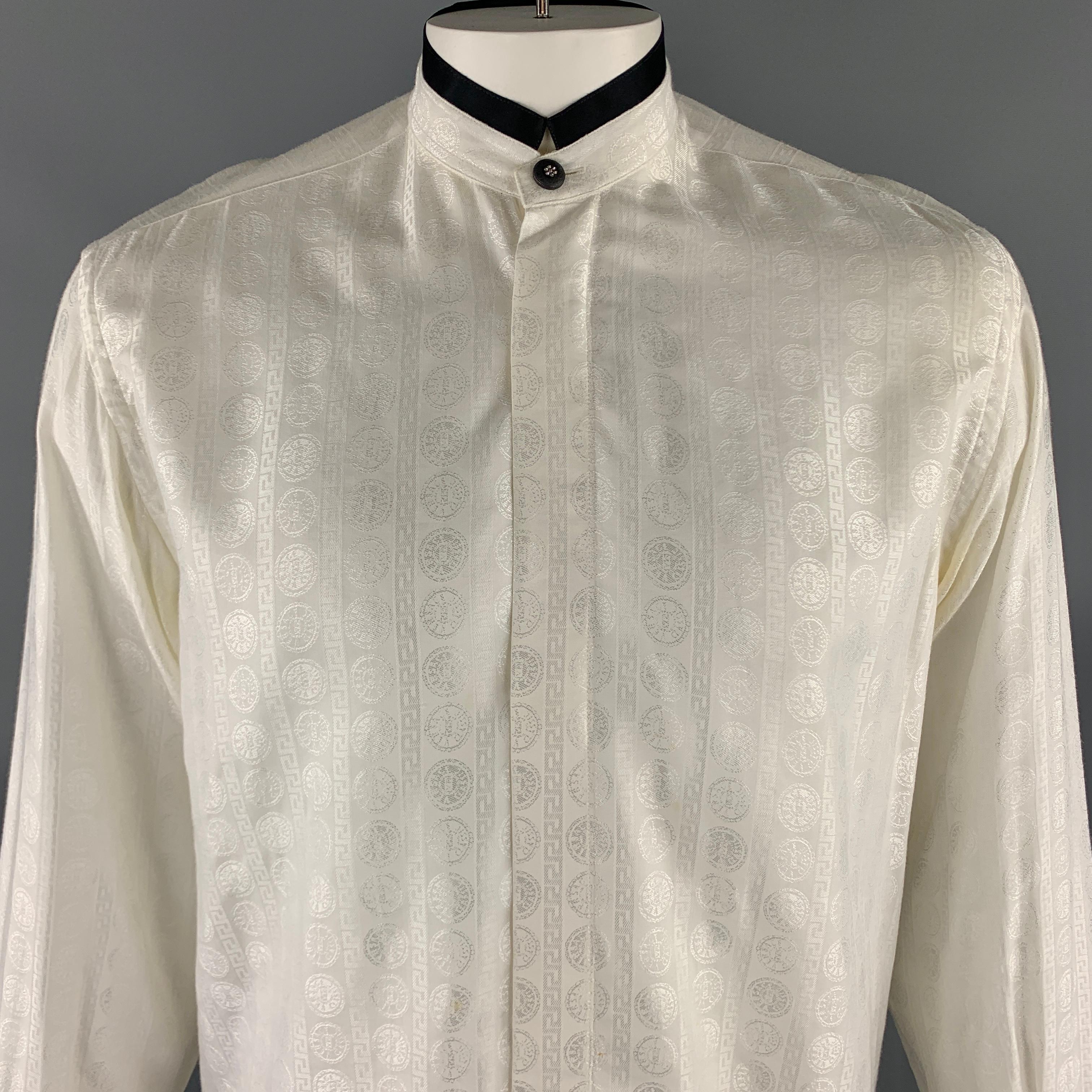 Vintage V2 by VERSACE long sleeve shirt comes in a textured cream cotton / viscose material, featuring a nehru collar, a contrast black trim, a rhinestone embellished button at collar and cuffs, and hidden buttons at closure. As is. Made in
