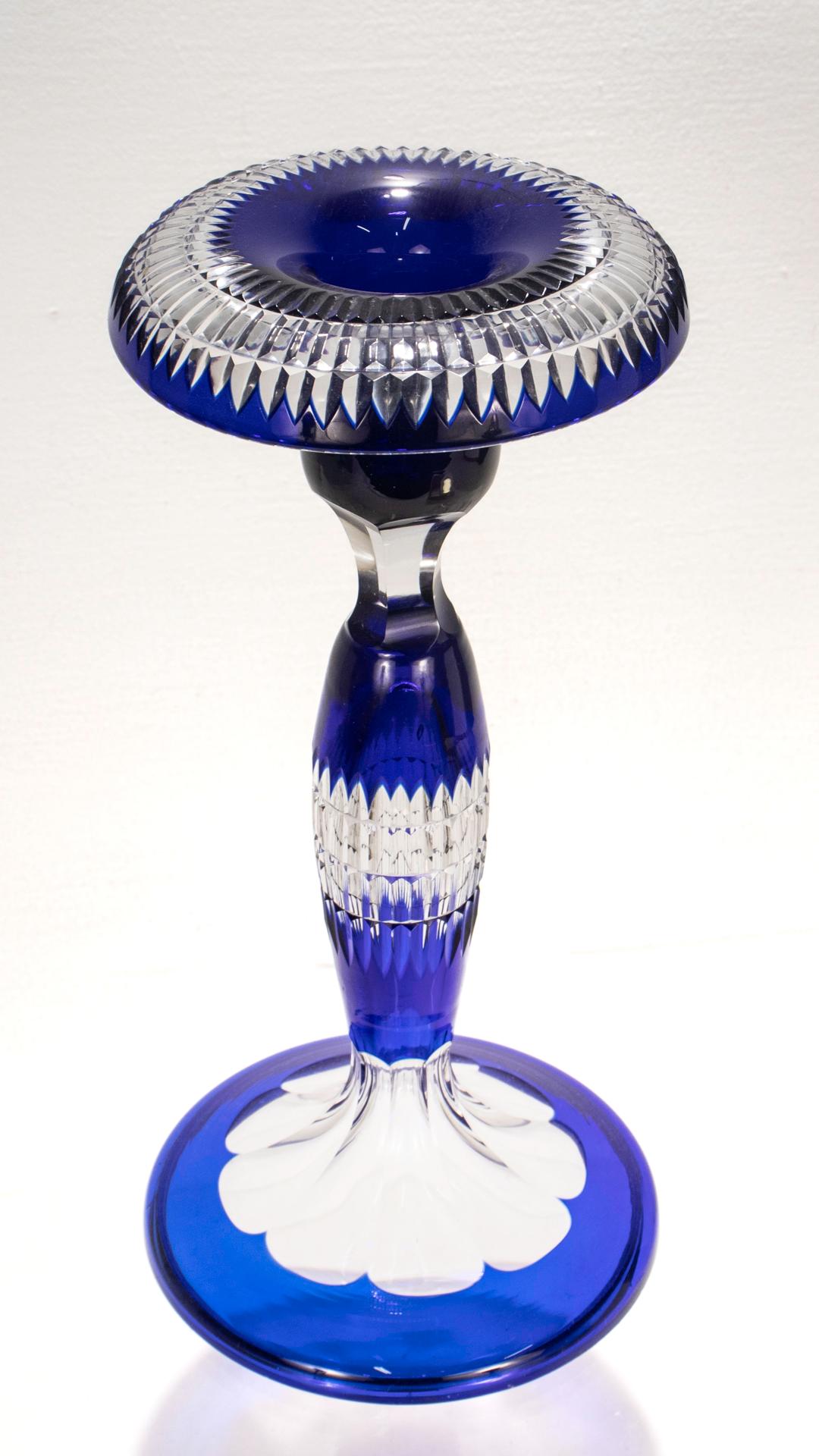 A fine blue cut-to-clear glass candlestick.

By Val Saint Lambert.

With a blue cased glass over a clear base, rows of deep cuts to the candle cup and pedestal, and panel cuts to the plunger shaped foot.

Simply an exceptional glass