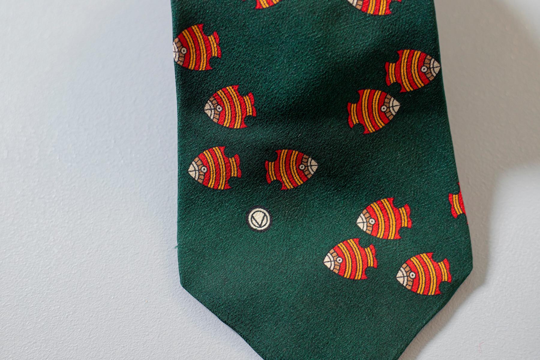 Designed by Valentino, this tie mirrors the Italian most light-hearted side. Made in all silk, this tie displays a group of orange fish swimming on a dark green background. Playful and fun, this tie is perfect for a party with your friends.