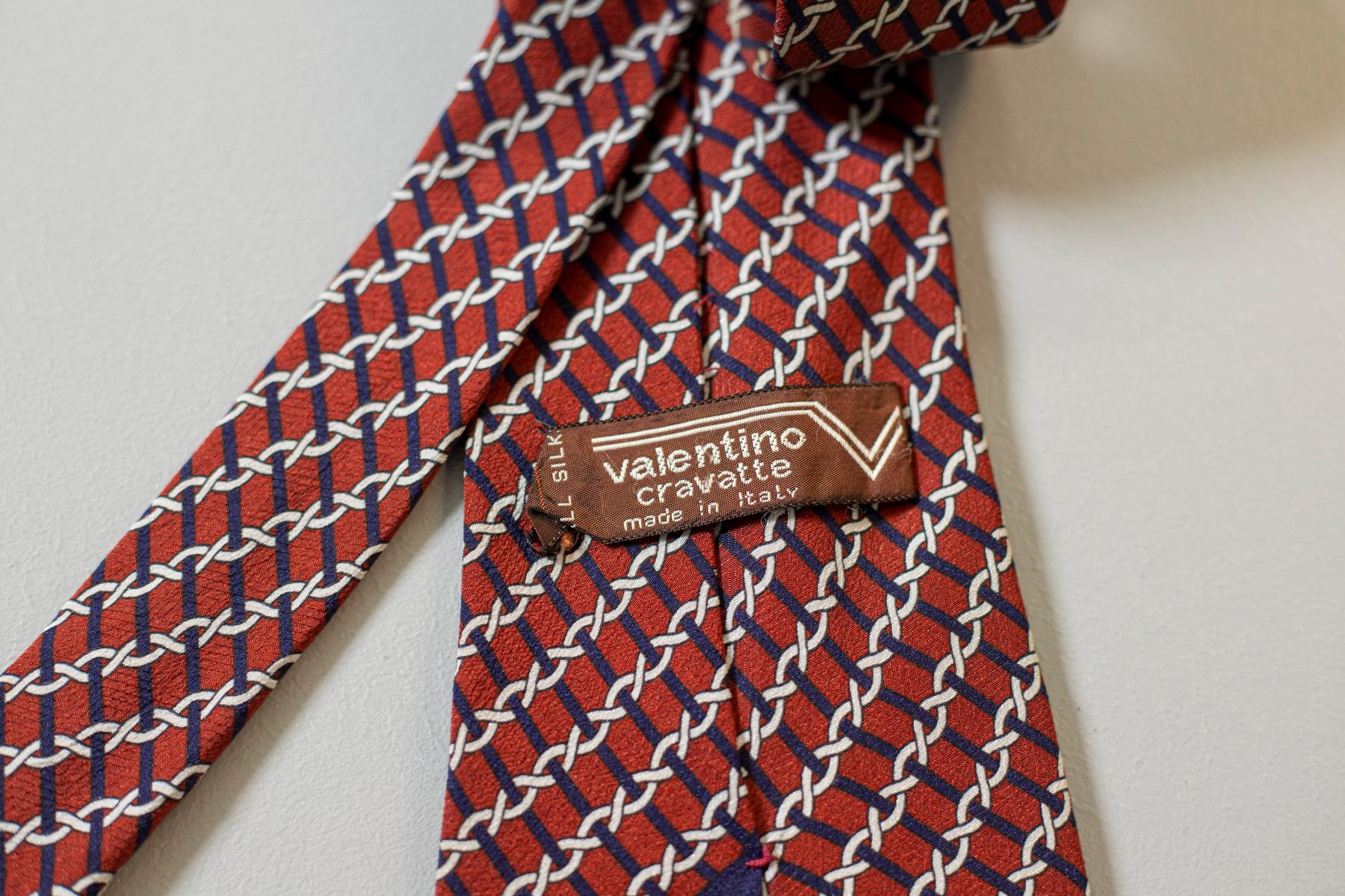 Decorated with blue stripes and white chain on an intense red background, this all-silk tie was designed by Valentino and made in Italy. It is classy and fine, yet original and unique: perfect for everyone who wants to add a touch of colour on a