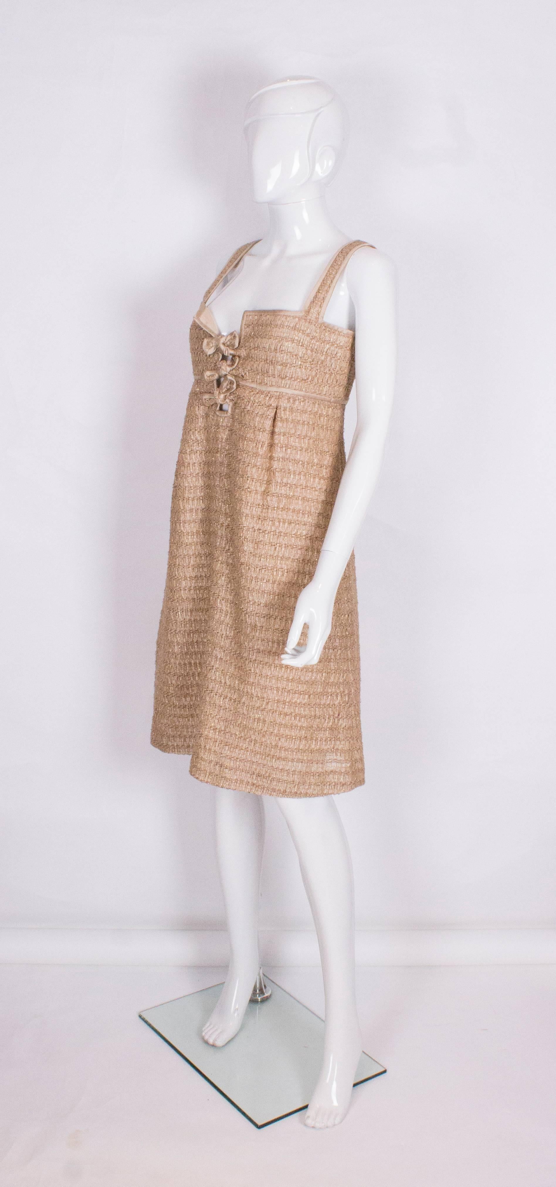 A chic cocktail  dress by Valentino Roma.The dress is in a soft gold fabric with silk lining in the bust area and linen like fabric for the body.The dress has 3 bows on the bodice area with silk trim and a central back zip.