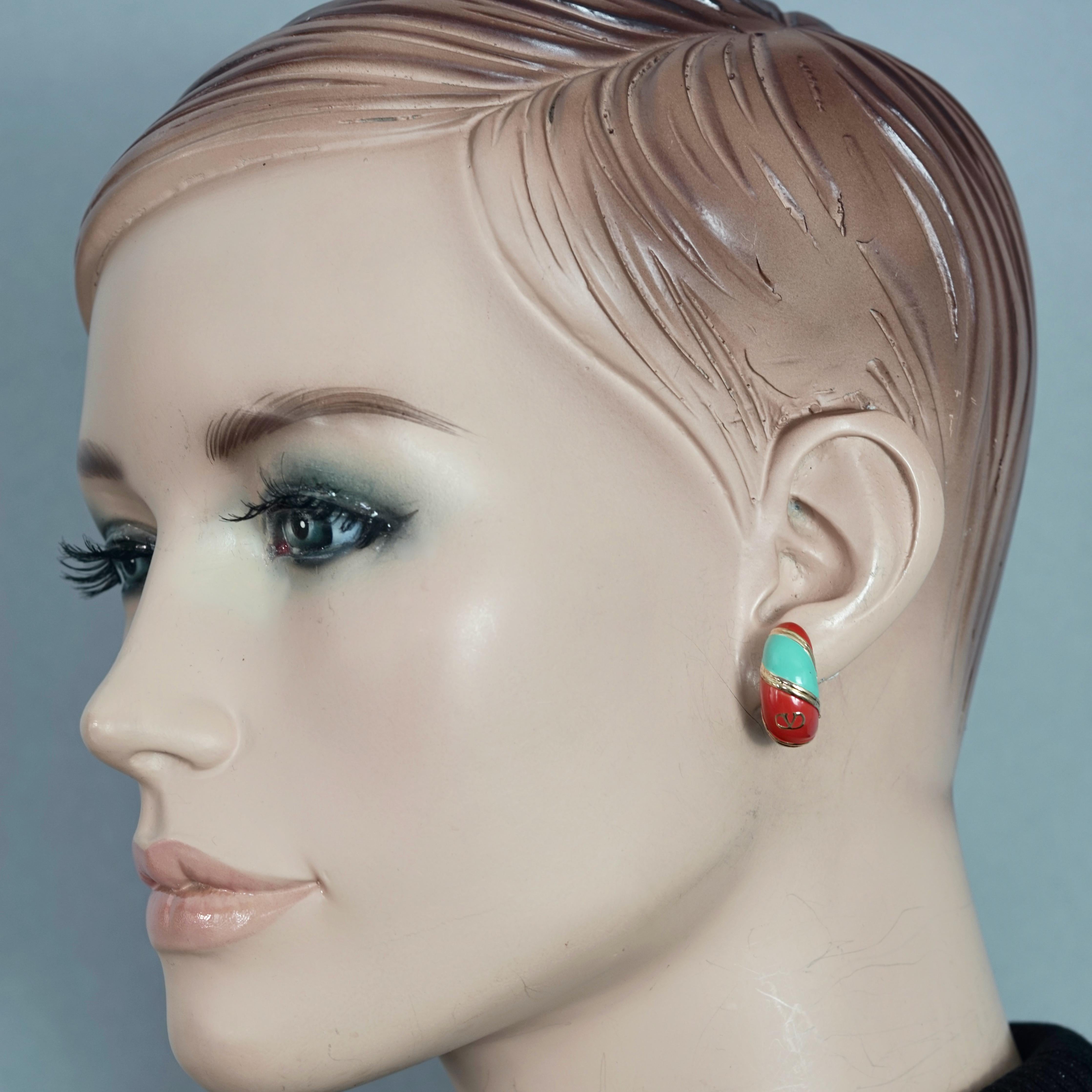Vintage VALENTINO V Logo Enamel Earrings

Measurements:
Height: 0.90 inches (2.3 cm)
Width: 0.39 inch (1 cm)
Weight per Earring: 6 grams

Features:
- 100% Authentic VALENTINO.
- Valentino V logo earrings with blue and orange enamel.
- Gold tone