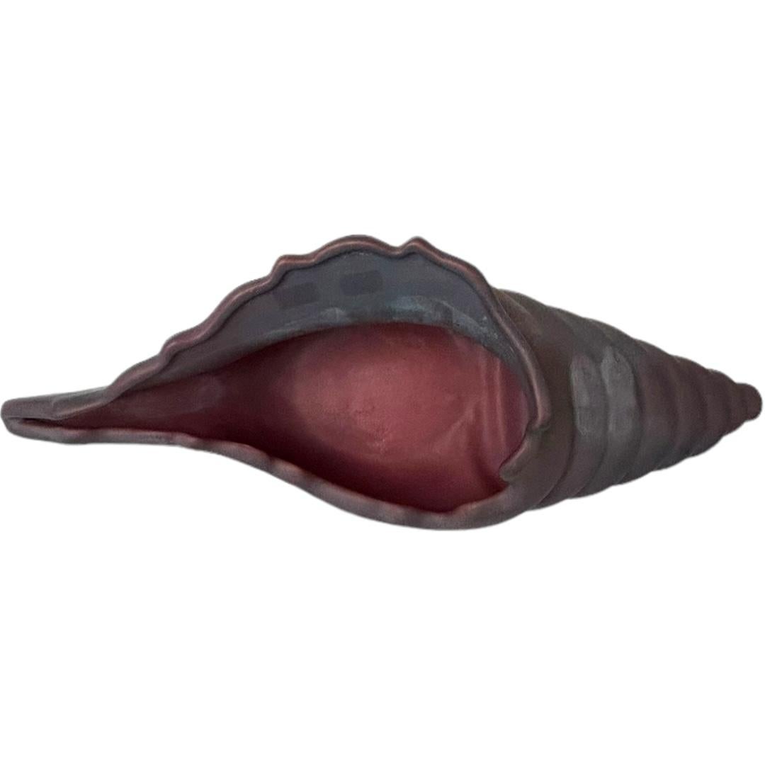 This vintage Van Briggle sculpture features a beautiful conch sea shell design in a dark mauve color.  The piece was made in Colorado Springs and has a unique pattern of the shell.  It is a rare original vase and signed on bottom.  It is perfect for